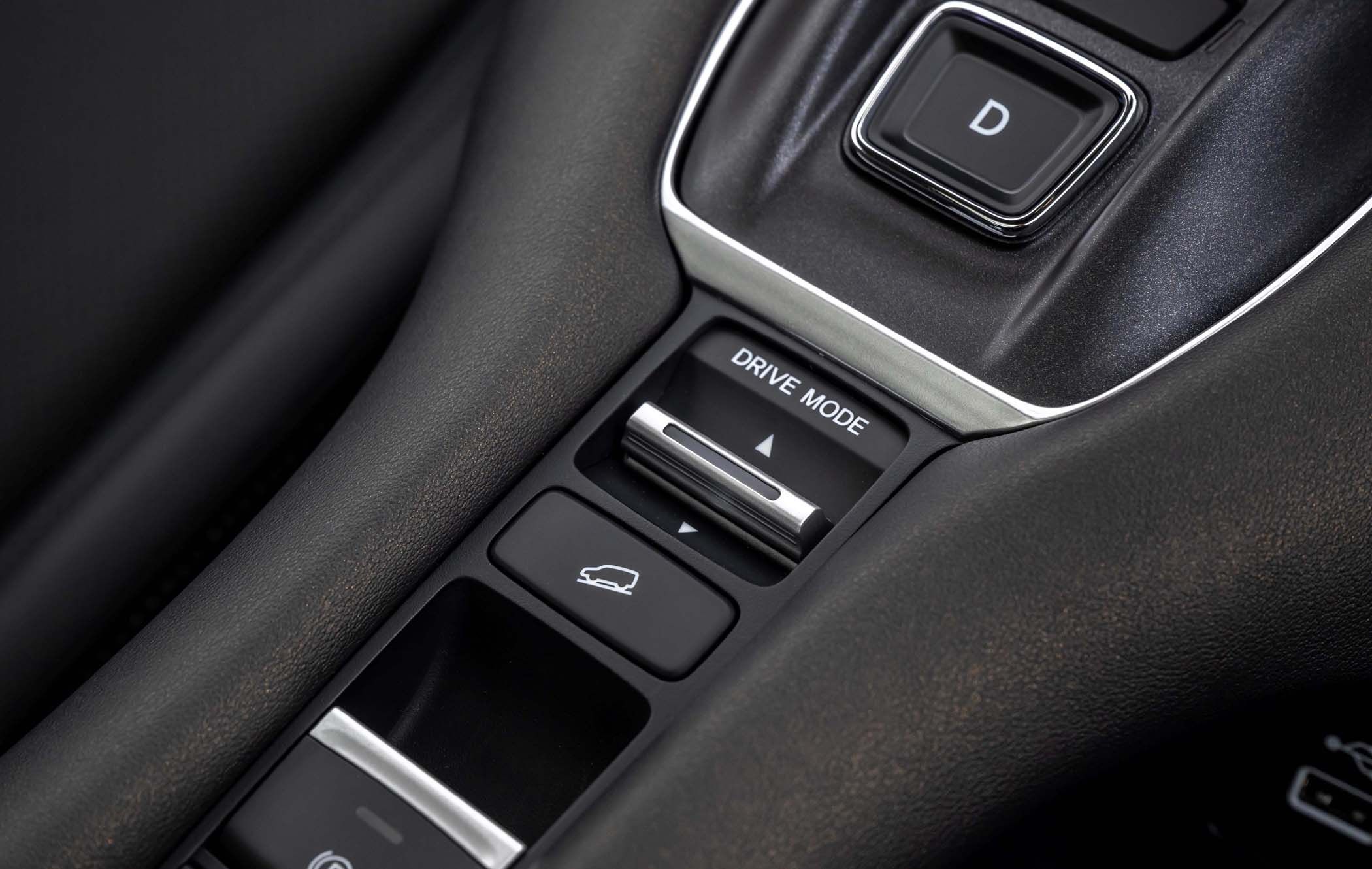 Close-up of a Honda ZR-V's centre console showing the drive mode selector, a gear shift button labeled "D," and a button for activating the parking brake.