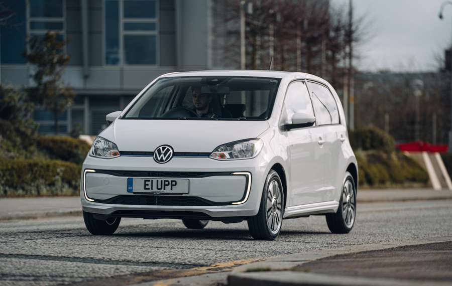 White Volkswagen e-Up driving along town road