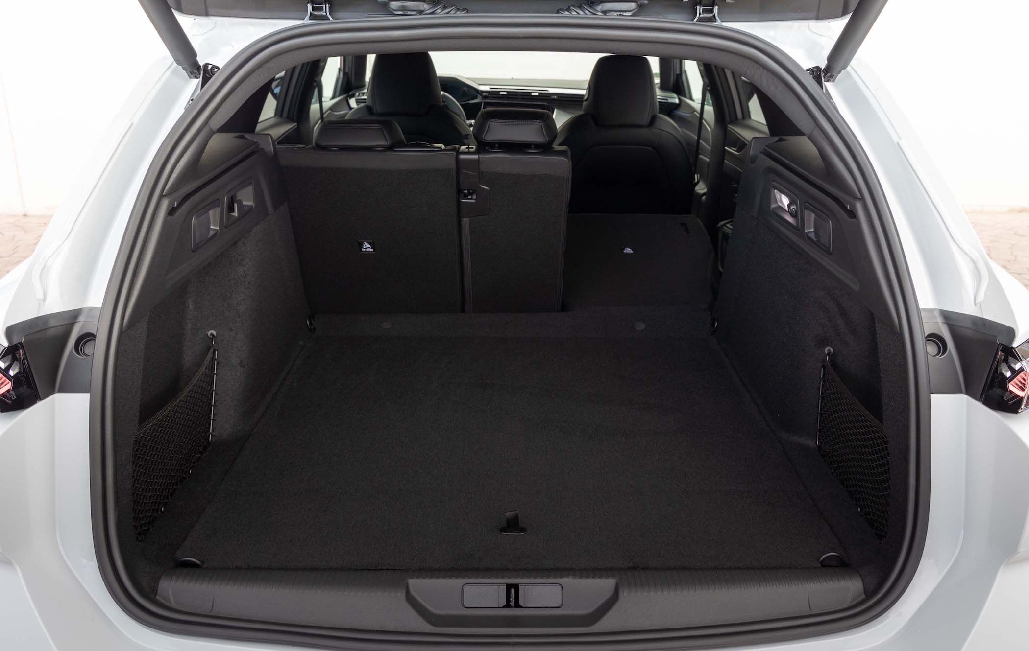 Open Peugeot e-308 SW boot with spacious luggage area, rear seats partially folded down, and side storage nets visible.