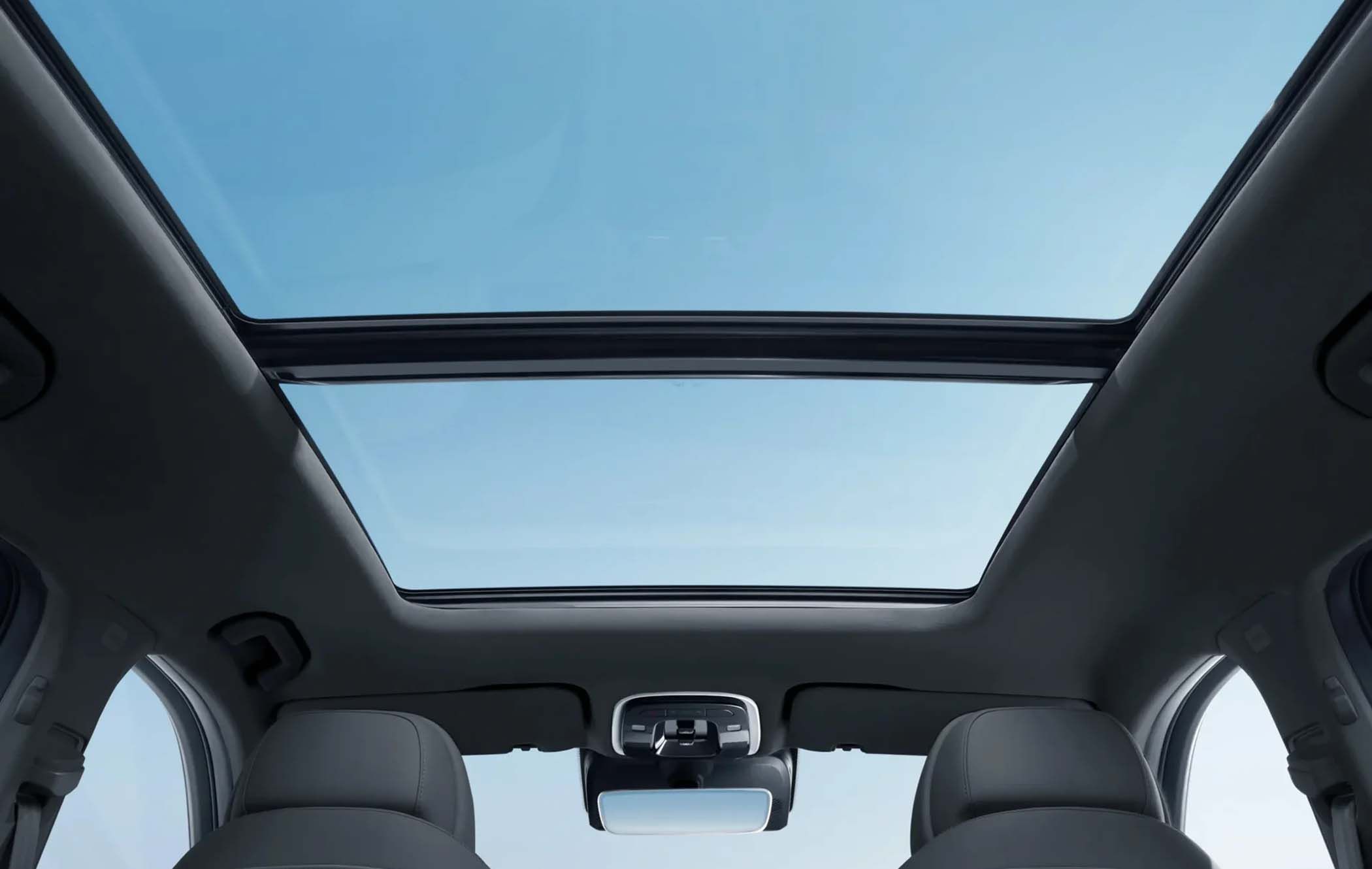 Interior view of an OMODA 9 featuring a large panoramic sunroof against a clear blue sky.
