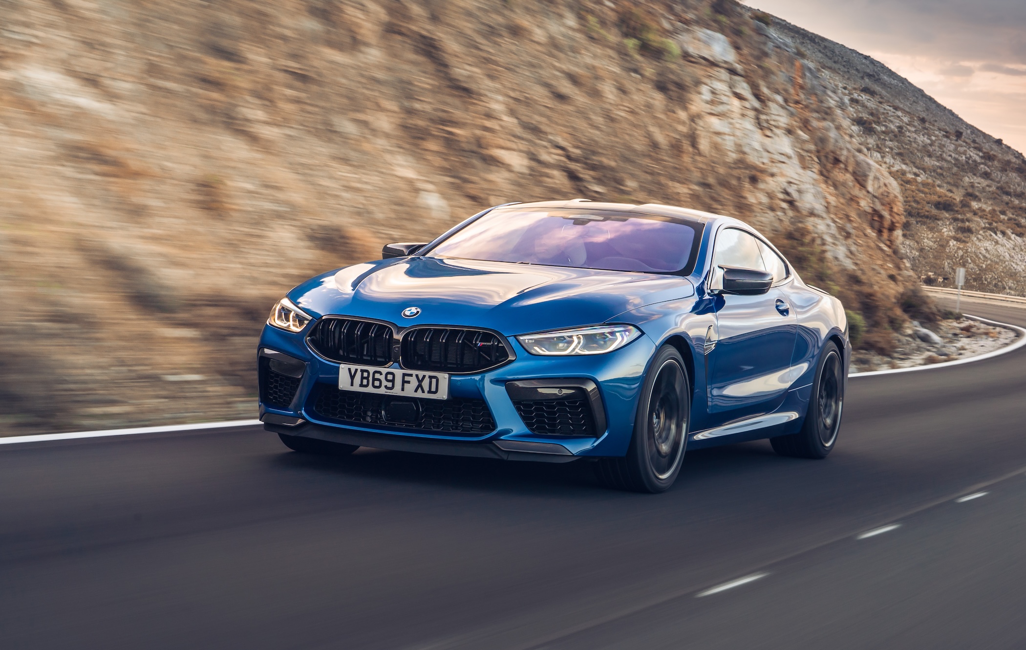 Blue BMW M8 Coupe driving along road