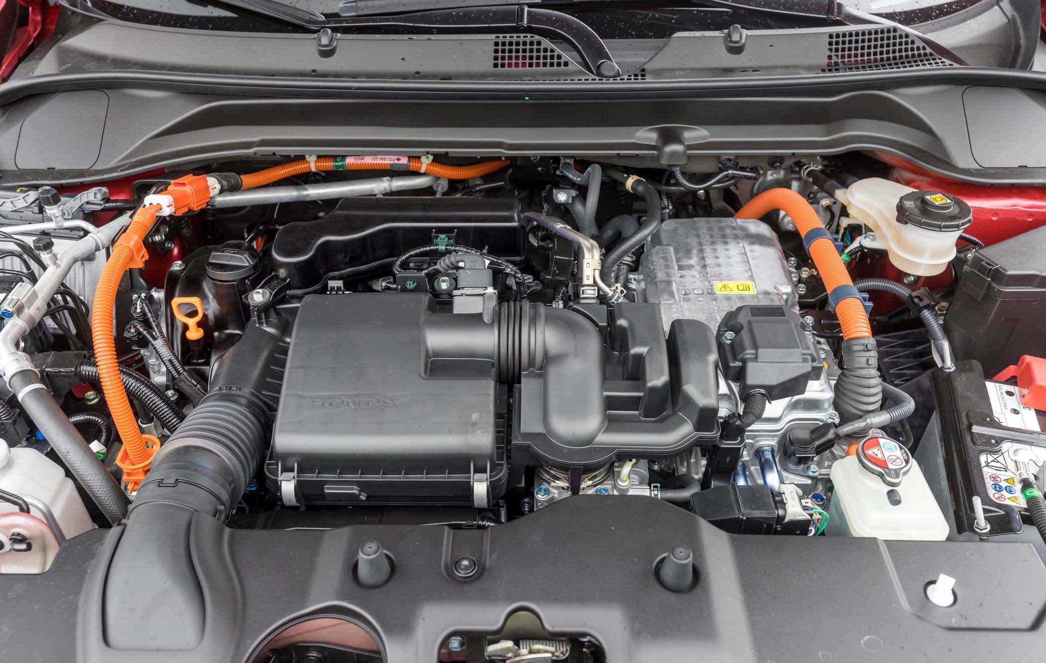 Close-up of a Honda HR-V engine with visible components, including orange cables, black air filter box, and various metal parts.