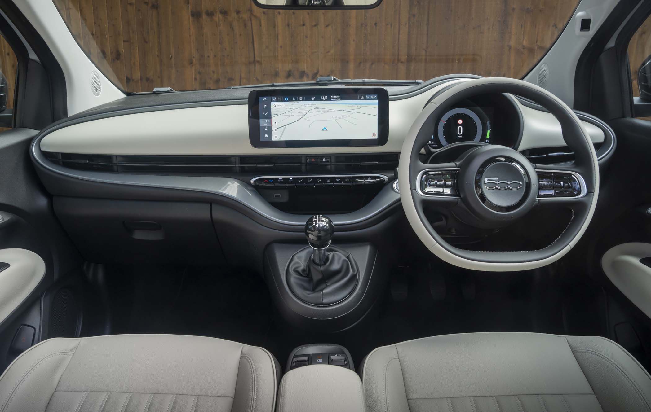 Fiat 500 Hybrid interior with a modern dashboard, digital display, steering wheel, manual gear shift, and beige leather seats.