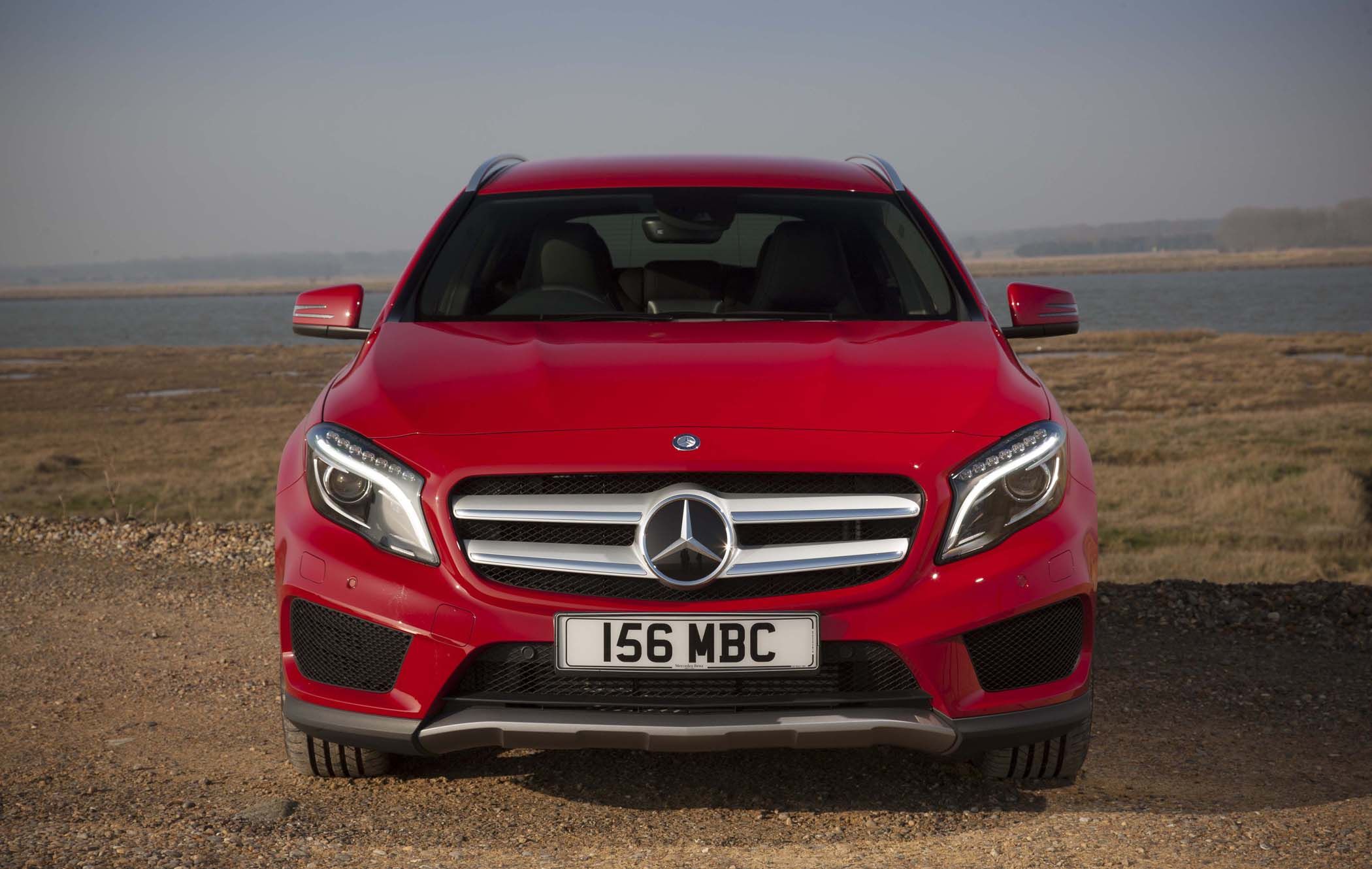 Red Mercedes GLA parked on a gravel road with a scenic, open landscape in the background.