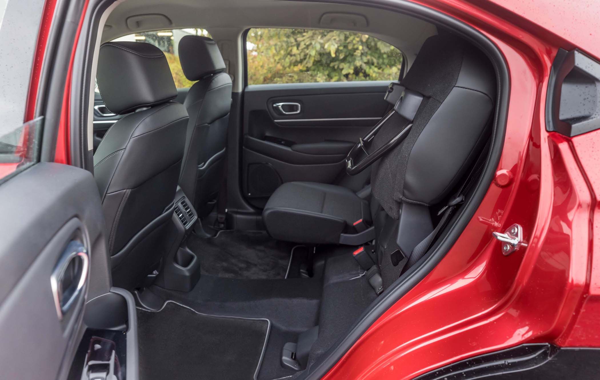 Interior of a Honda HR-V showing the back seat area with black upholstery, folded front passenger seat, and visible rear air vents.