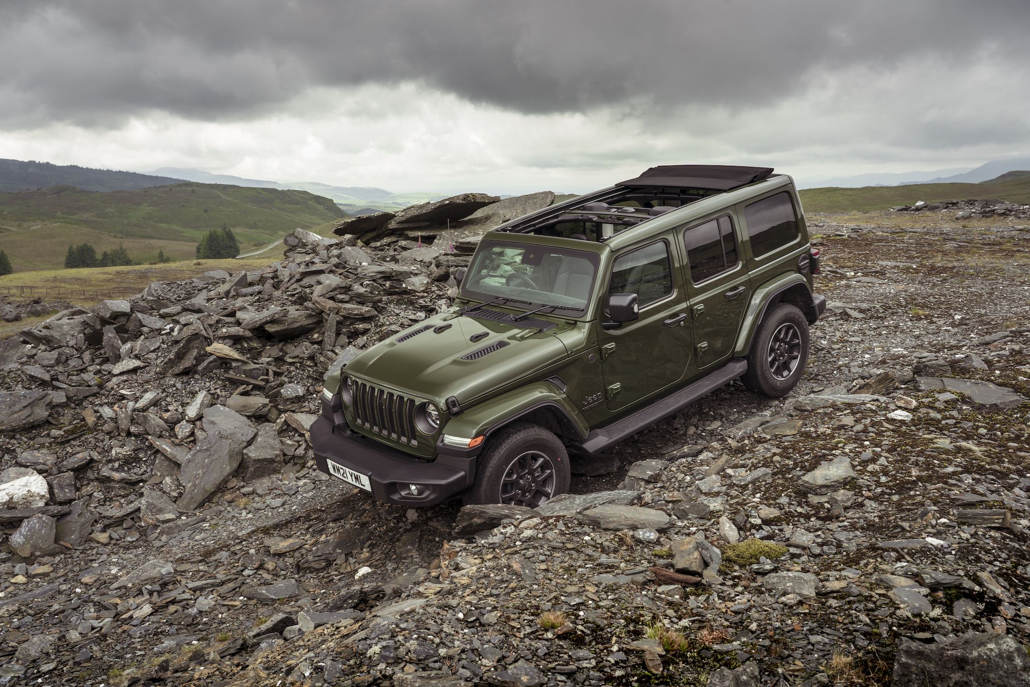 a dark green jeep wrangler off-road driving down a rocky hill