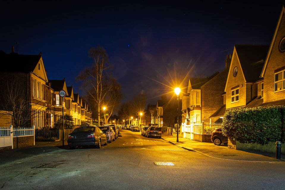 A UK street with parked cars at night