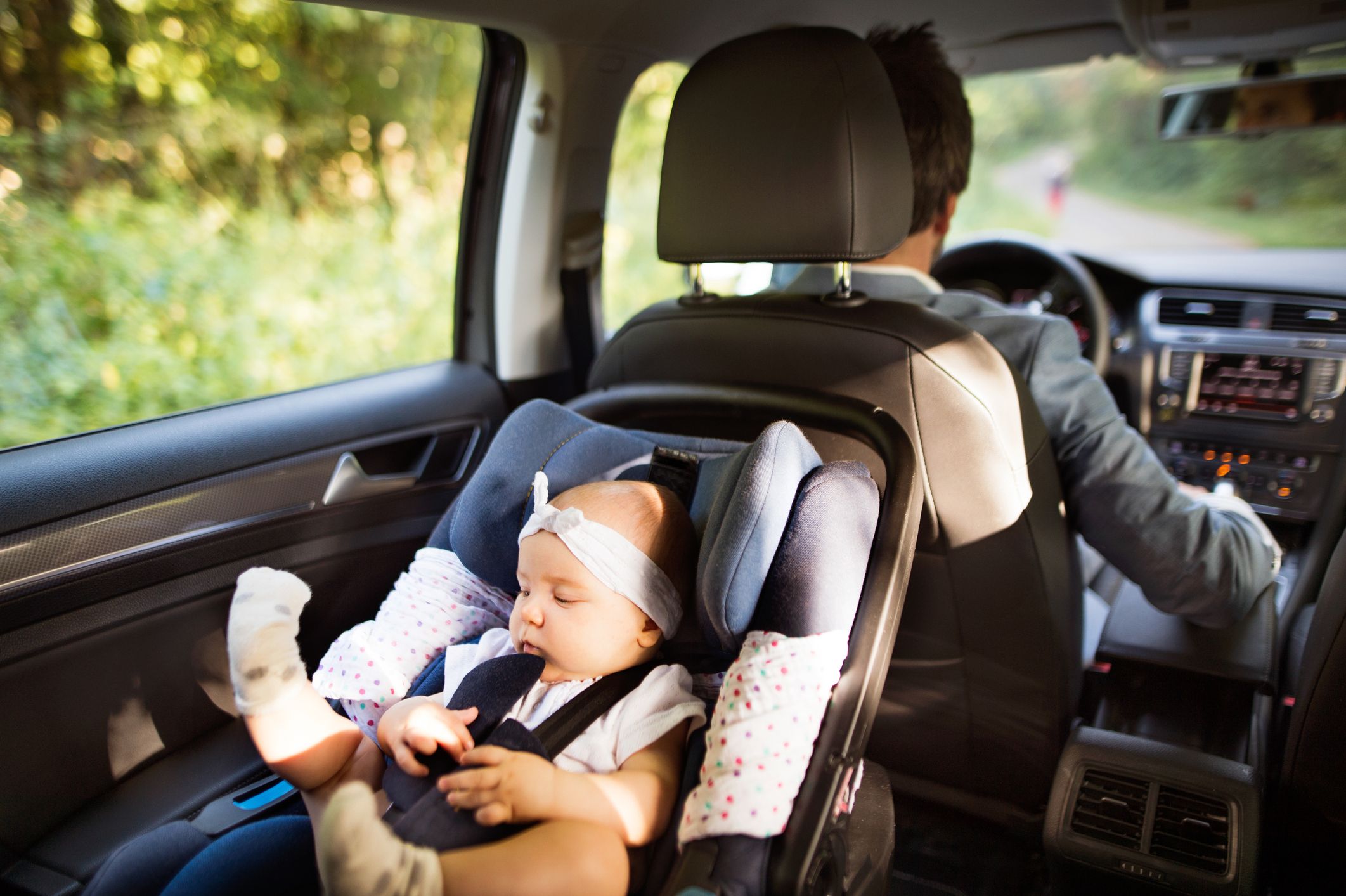 A baby sat in a rear-facing car seat in the back of a car