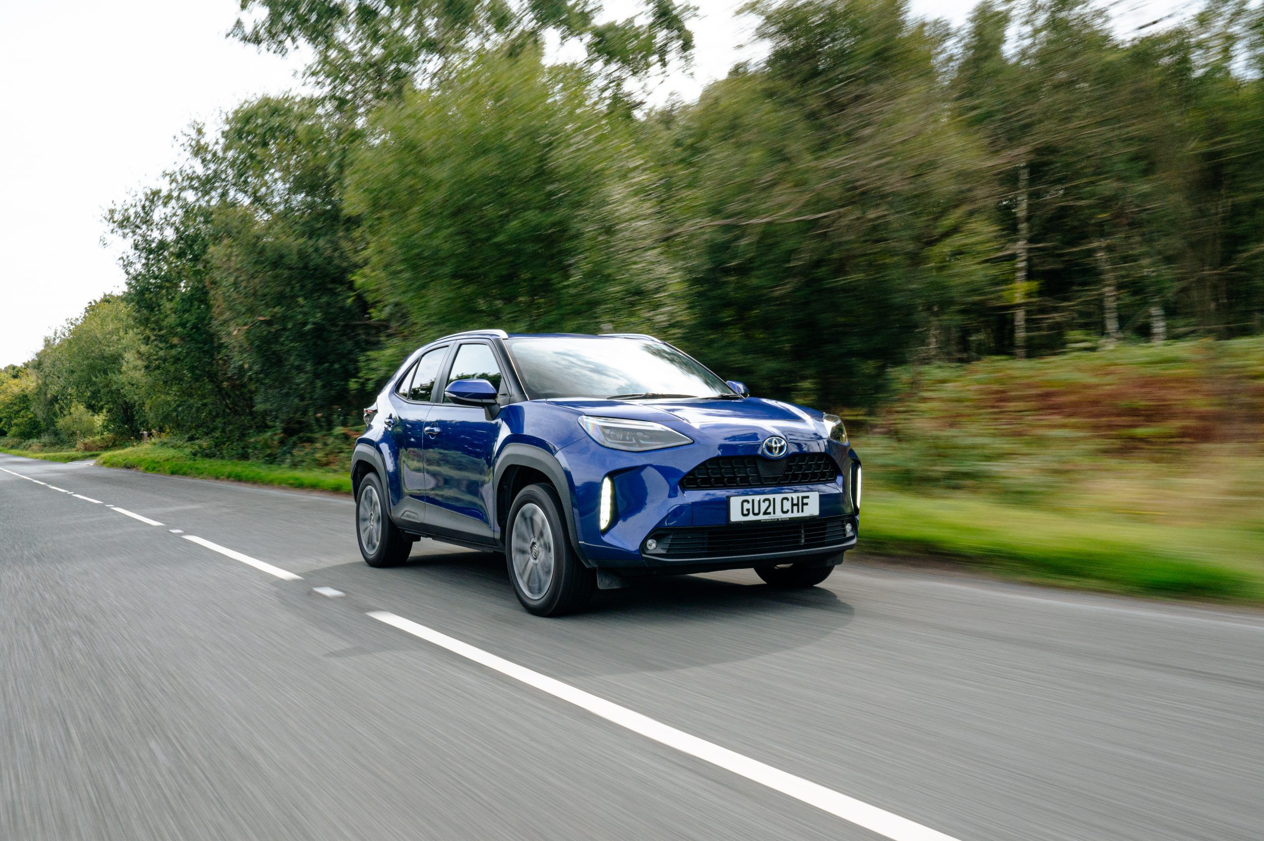 a blue toyota yaris cross driving on a country road