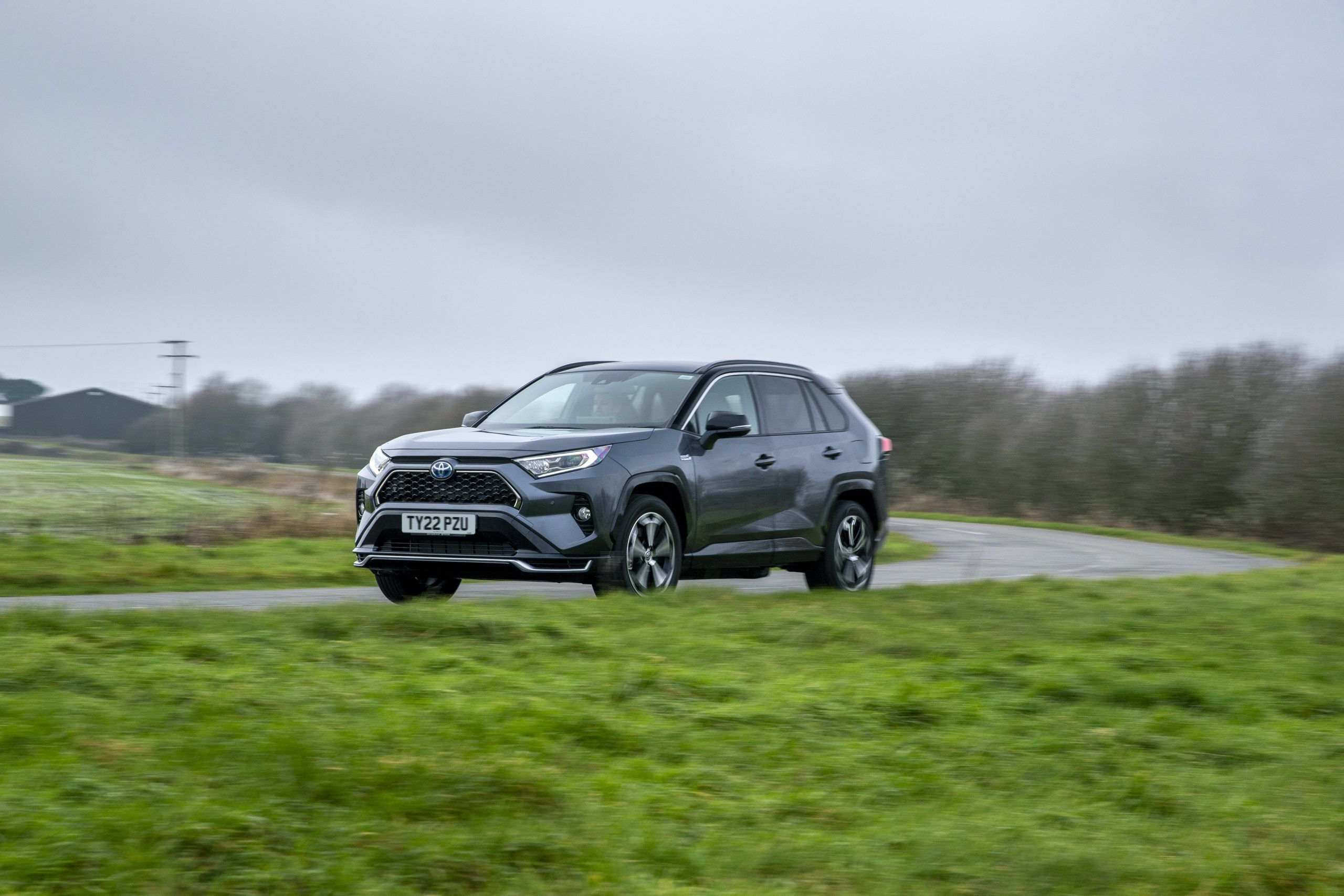 a grey Toyota RAV4 PHEV driving in the British countryside