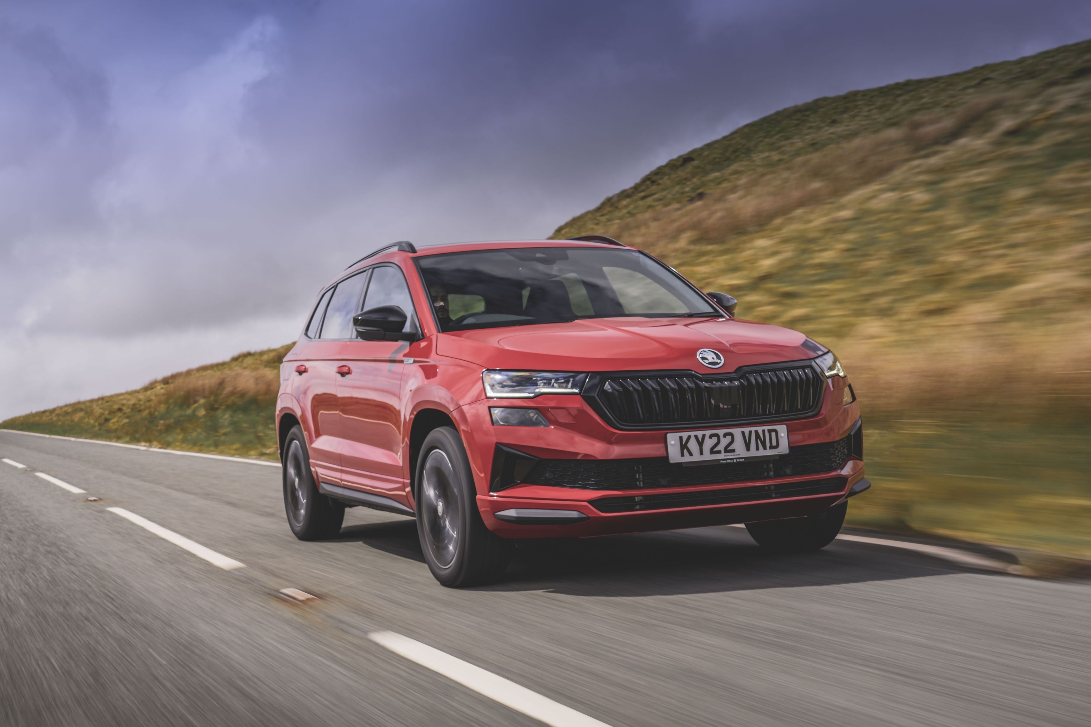 A red Skoda Karoq driving on a road