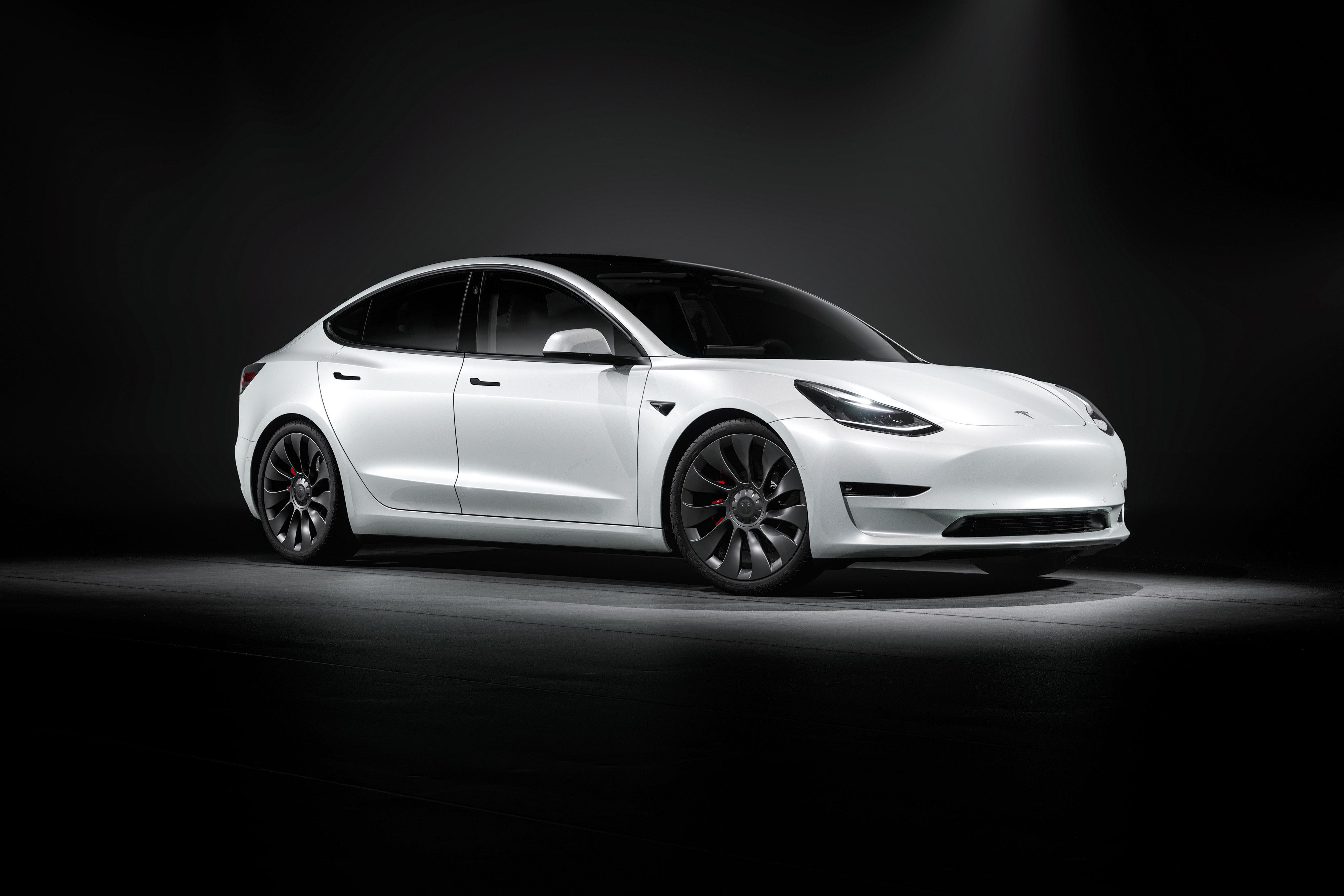 a white tesla model 3 parked in a black background