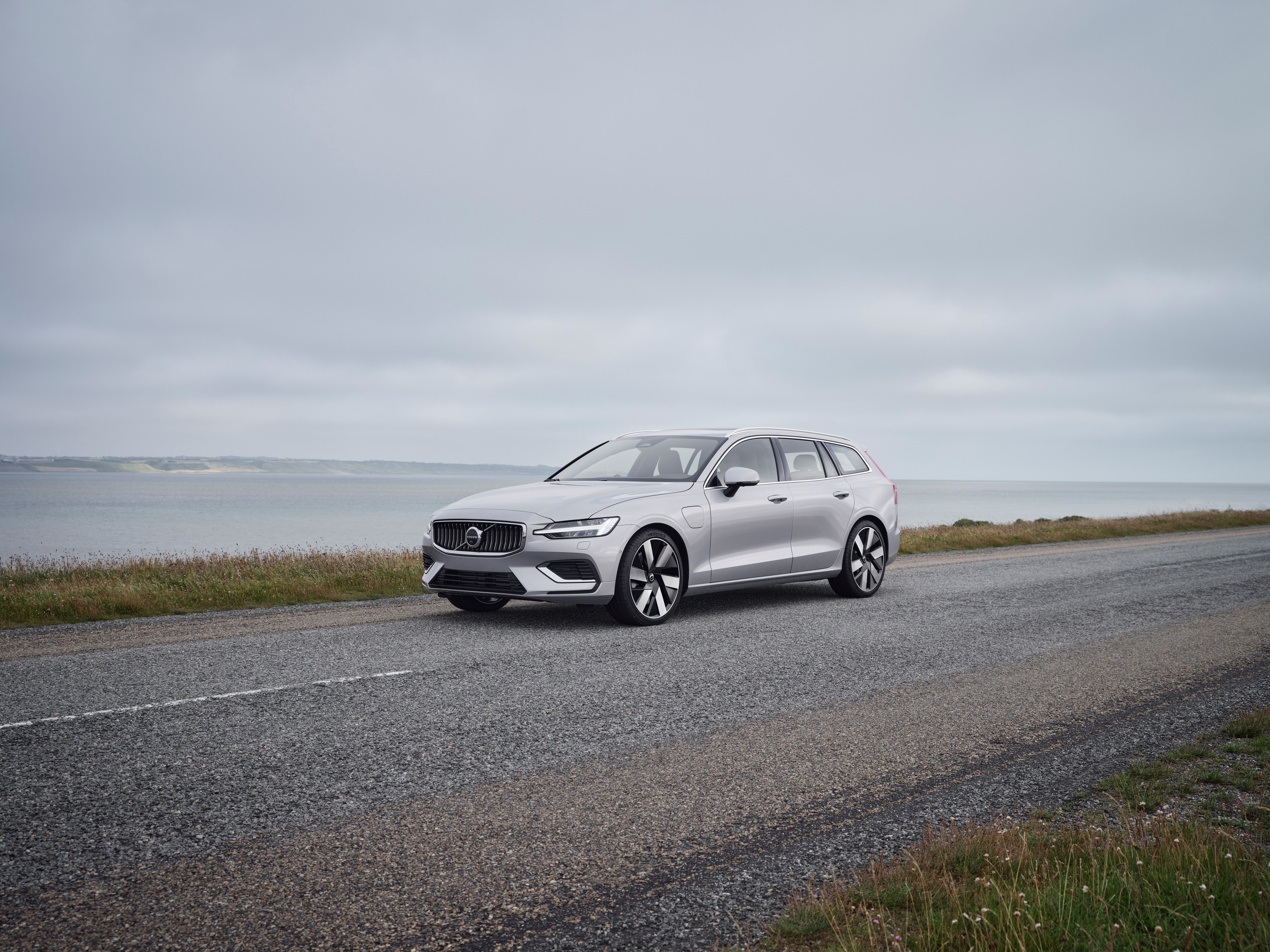 A grey Volvo V60 Recharge parked by the sea on the road