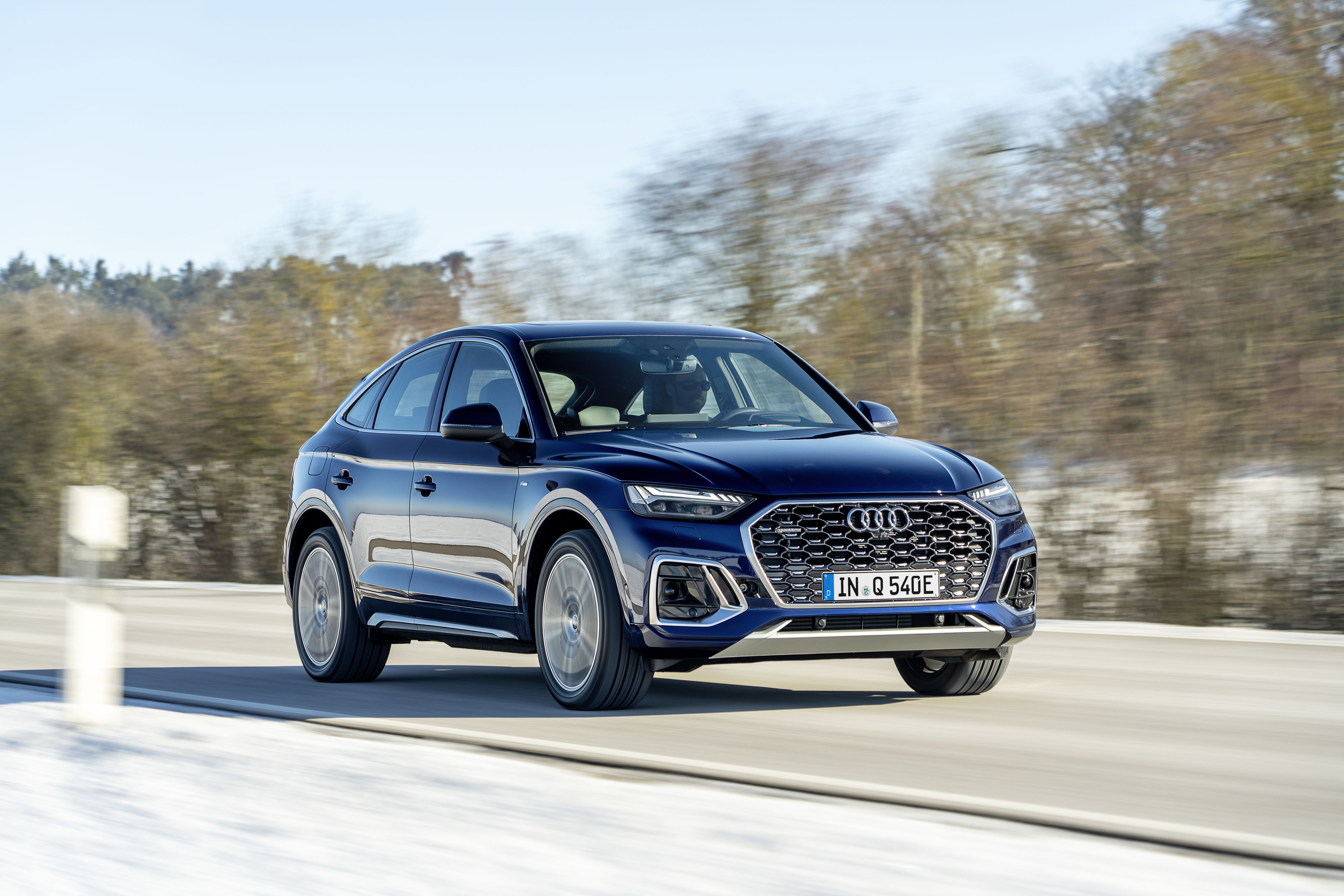 a dark blue Audi Q5 PHEV driving on a road in the snow