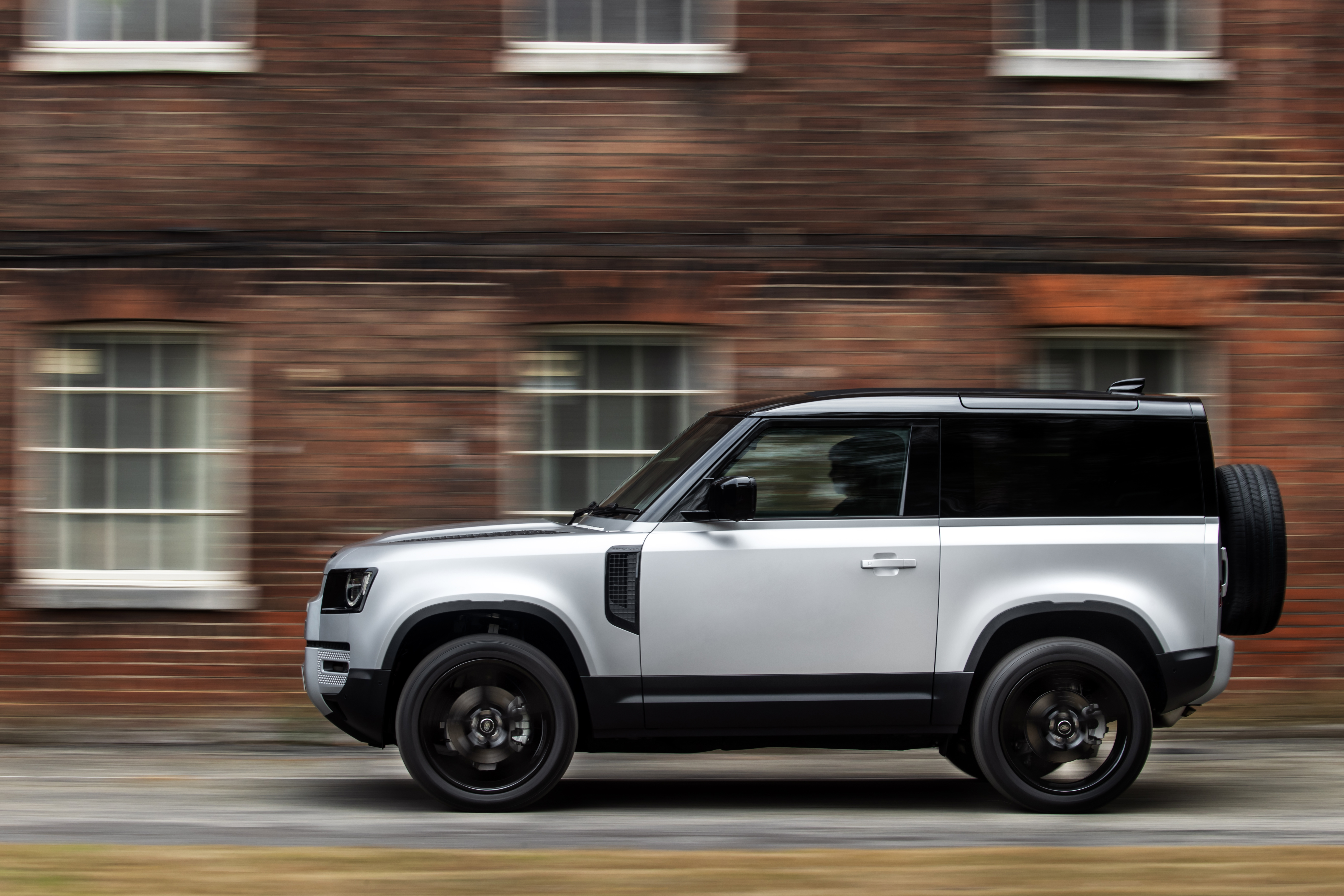 A silver Land Rover Defender from the side