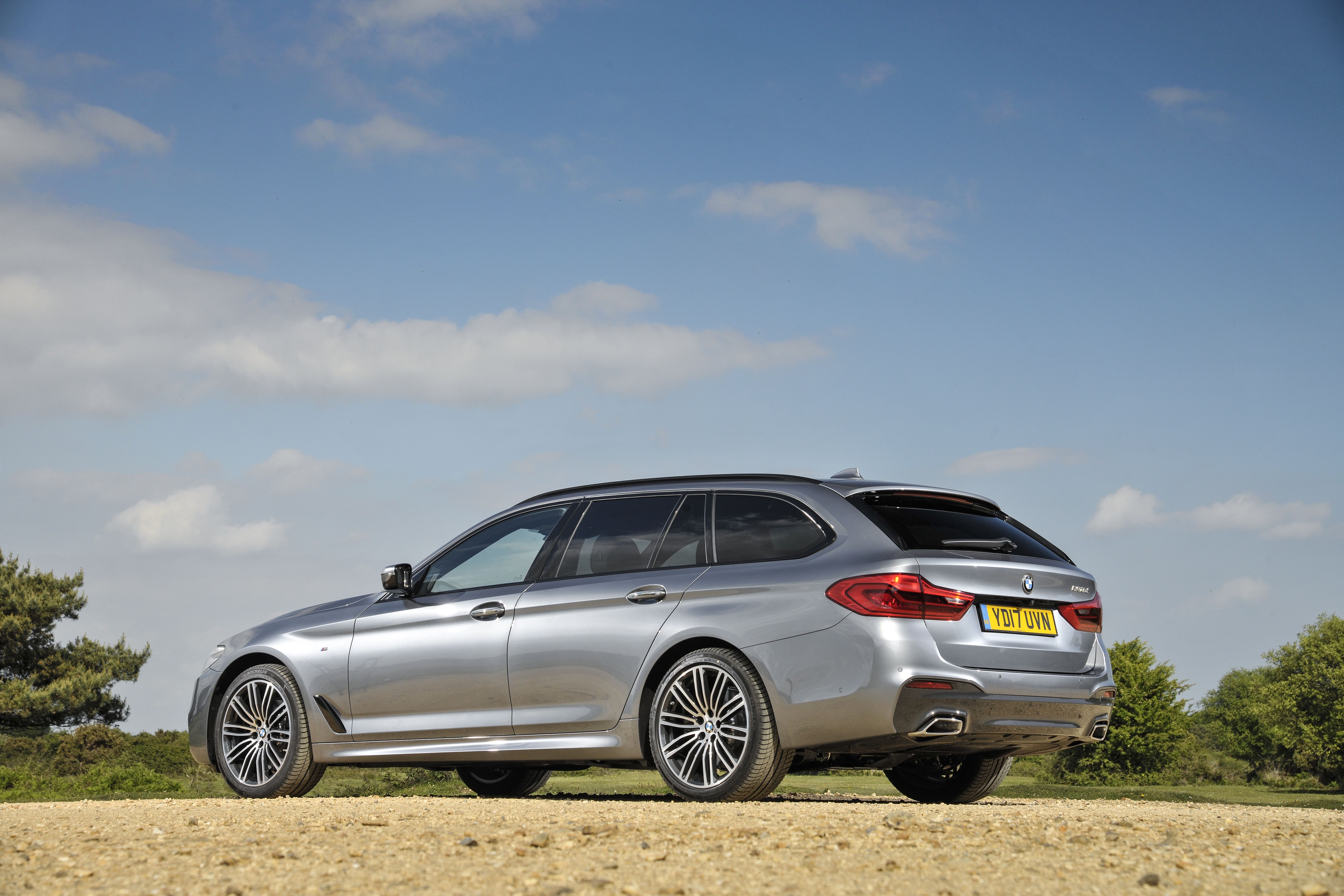 a grey bmw 5 series touring parked on dirt