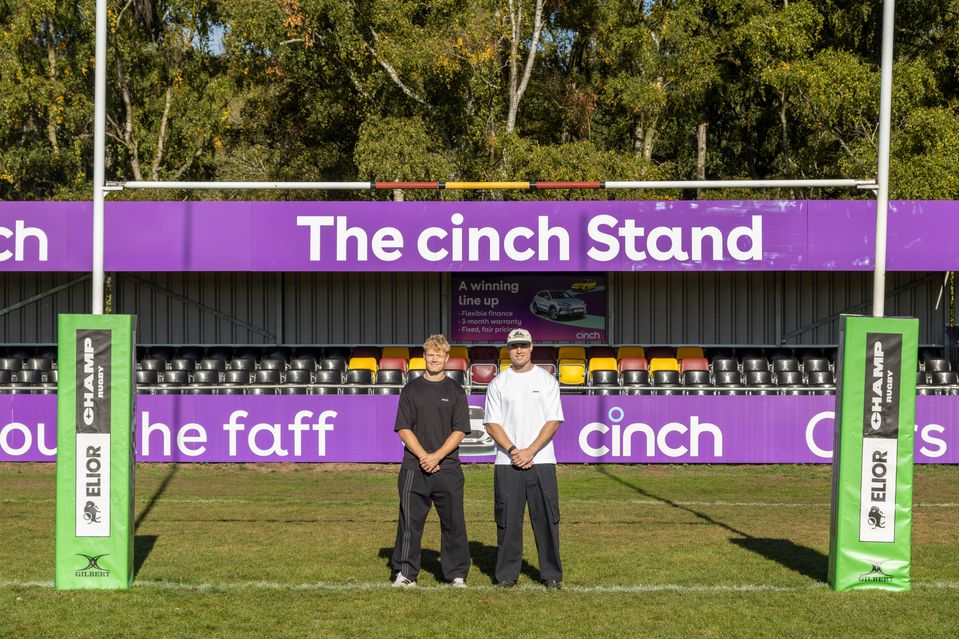 Tommy Freeman and Fin Smith in front of the cinch Stand at Ampthill Rugby Club