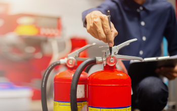 Image of person pointing at fire extinguisher gauge