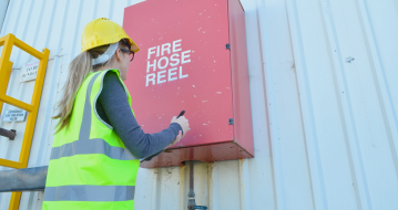 Person Looking At Fire Hose Reel While Carrying Out Inspection