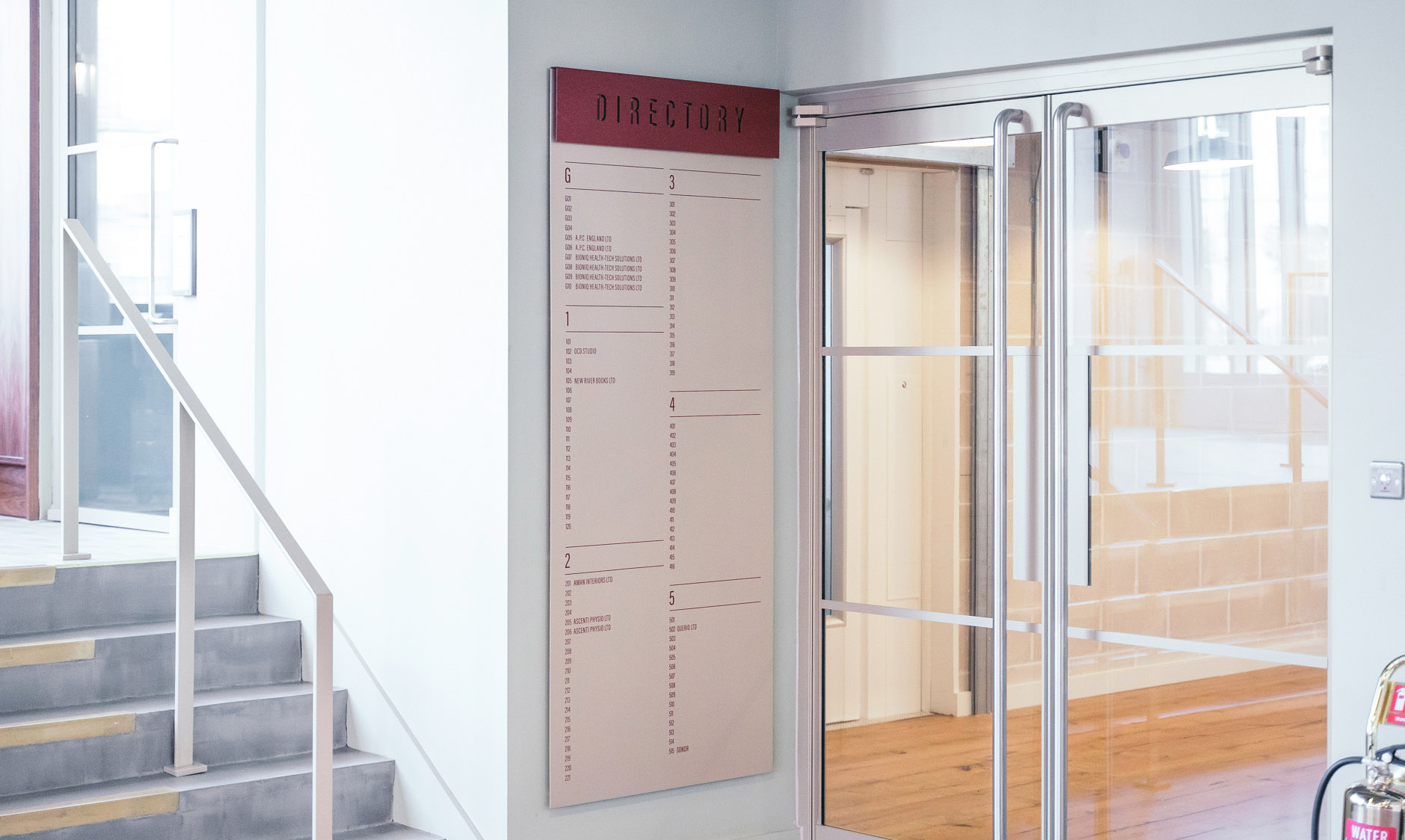 Bright modern lobby with a door-length wall directory panel to help people navigate Leroy House co-working space in London.