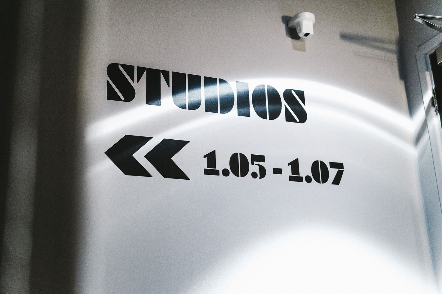 A large black vinyl sign with arrows and the word STUDIOS