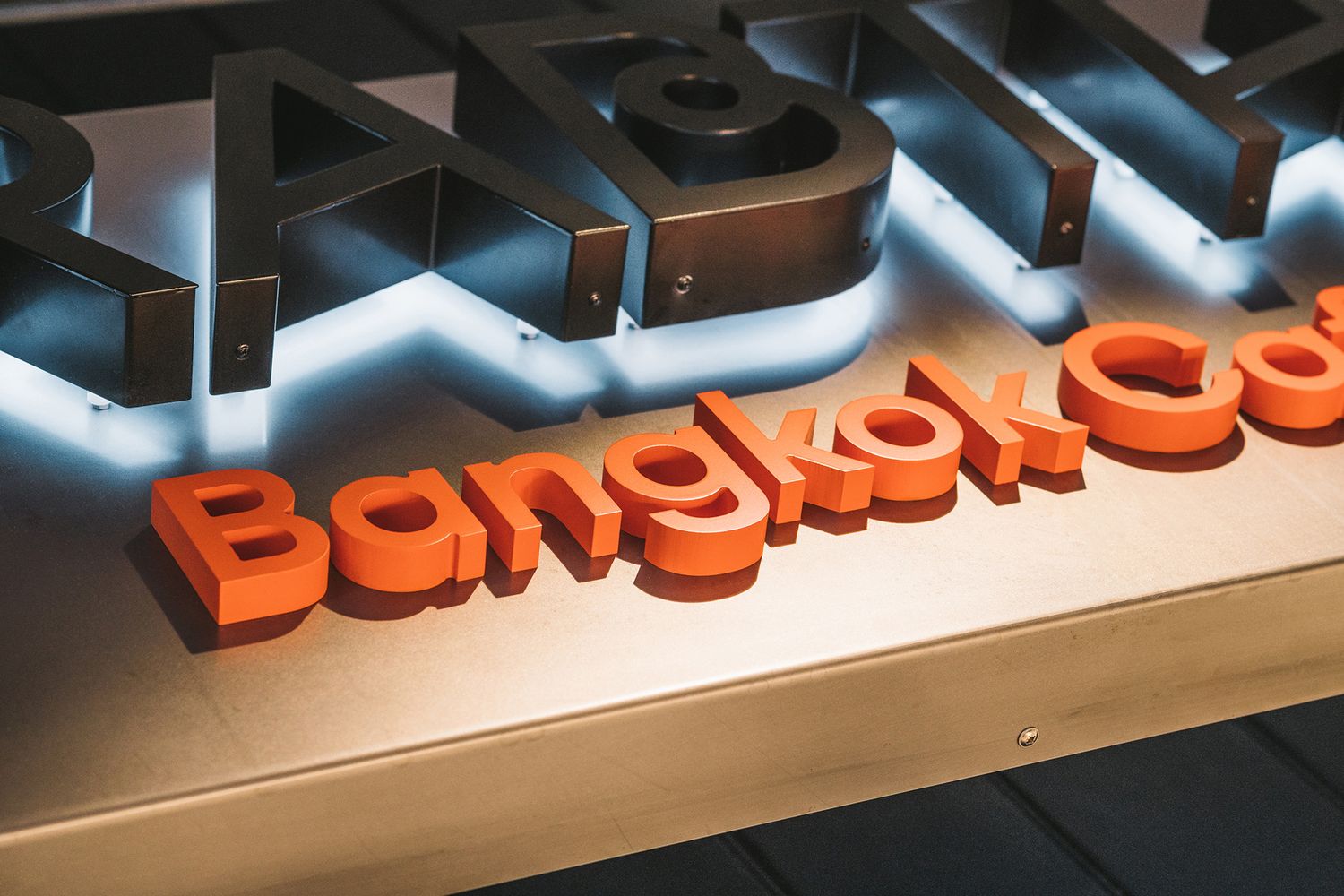 Close up of a restaurant sign using illuminated black and orange 3D lettering.