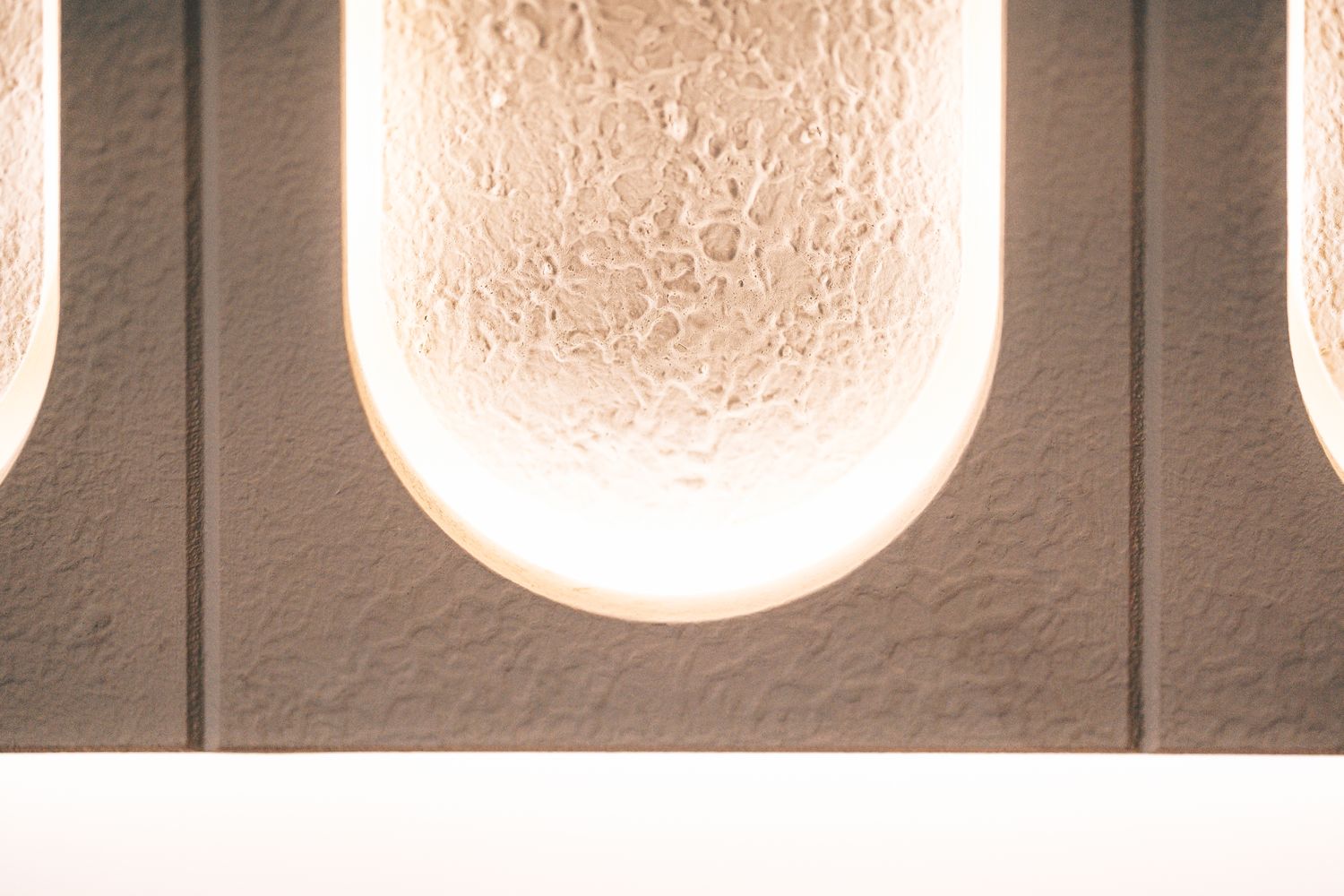 Close-up of the textured illuminated feature wall, showing the recessed ellipse forms and integrated LED halo lighting.