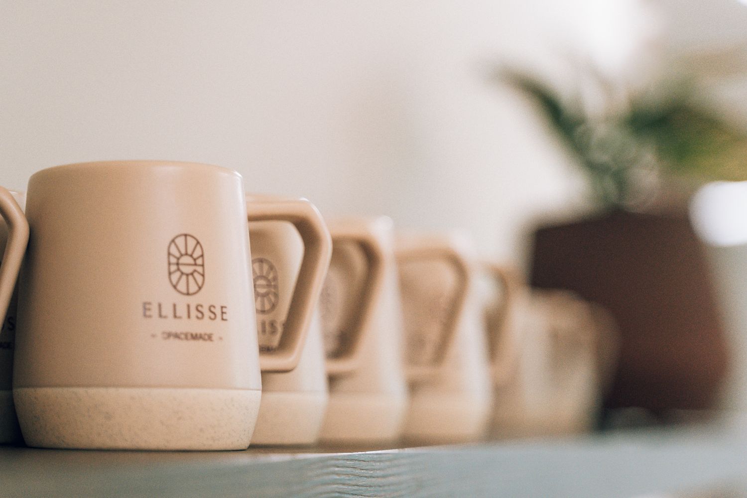 Branded Ellisse mugs within the co-working kitchen, extending the Spacemade location identity into the shared workspace.