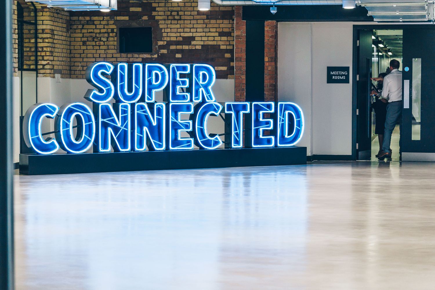 blue neon sign standing on the floor in the middle of the foyer