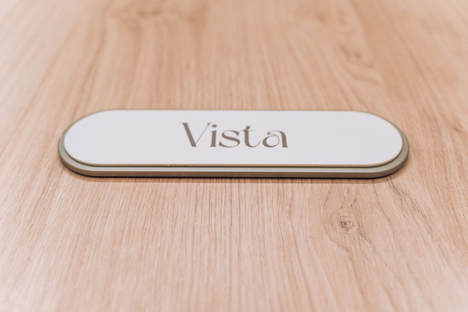 Custom meeting room name plaque for Vista at Ellisse, using the curved lozenge form developed across the signage system.