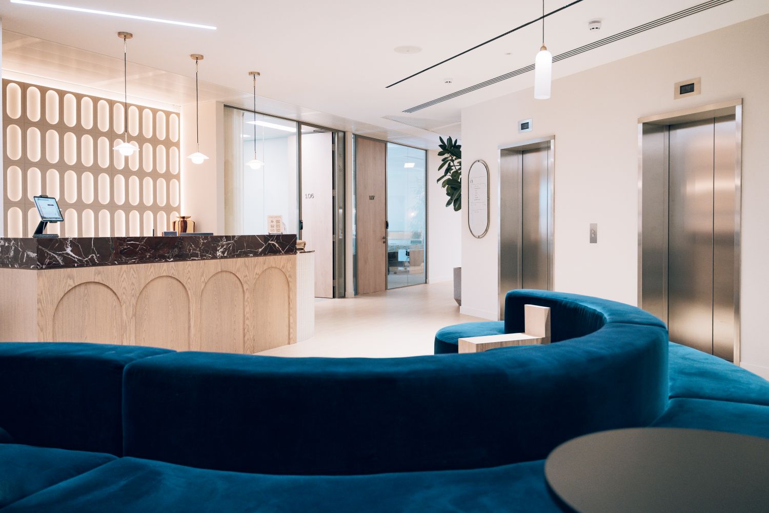 Ellisse reception and lift lobby featuring the illuminated feature wall, metal logo and bespoke office wayfinding signage.