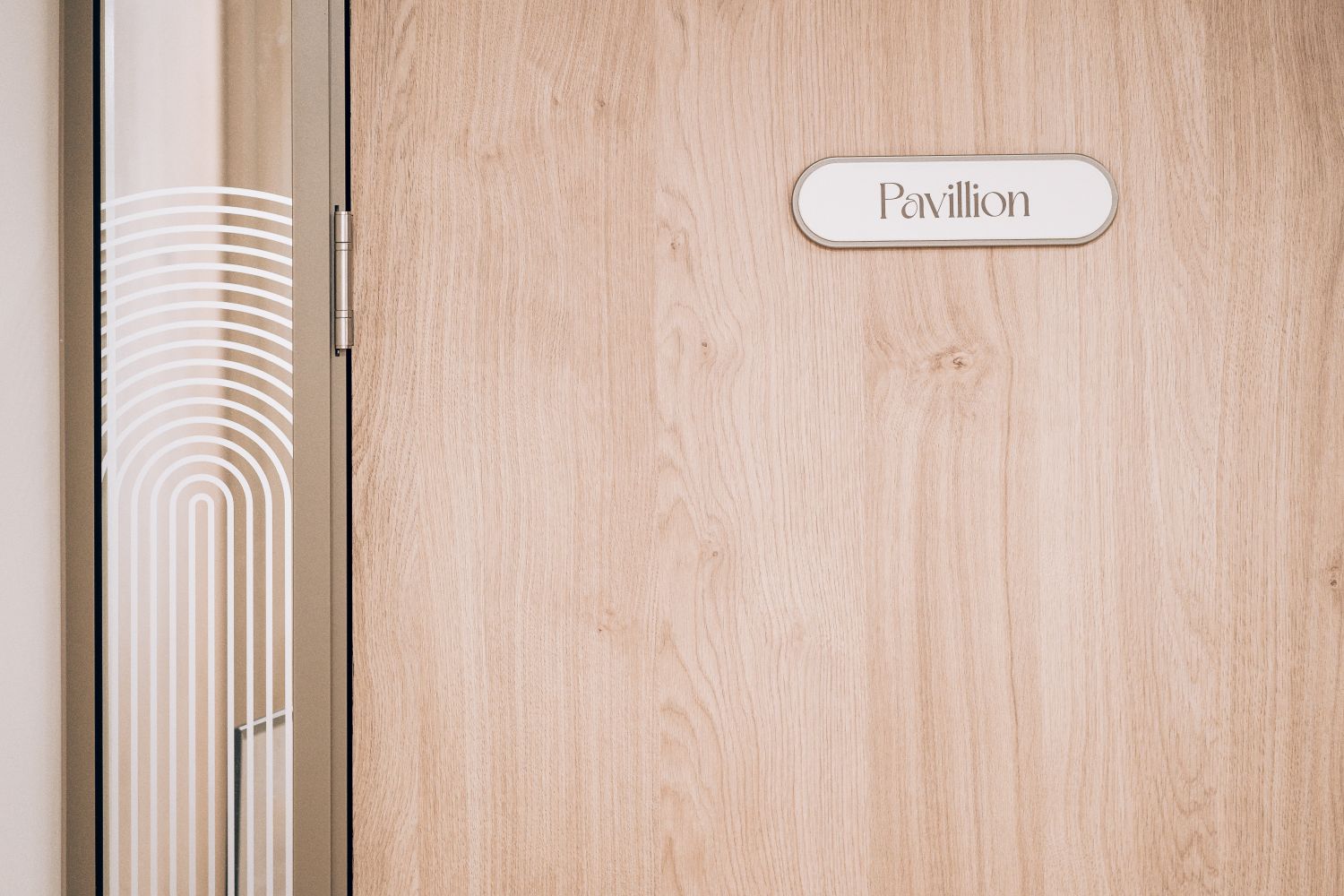Bespoke Pavilion meeting room plaque at Ellisse by Spacemade, using the curved lozenge form from the wider Art Deco signage system.