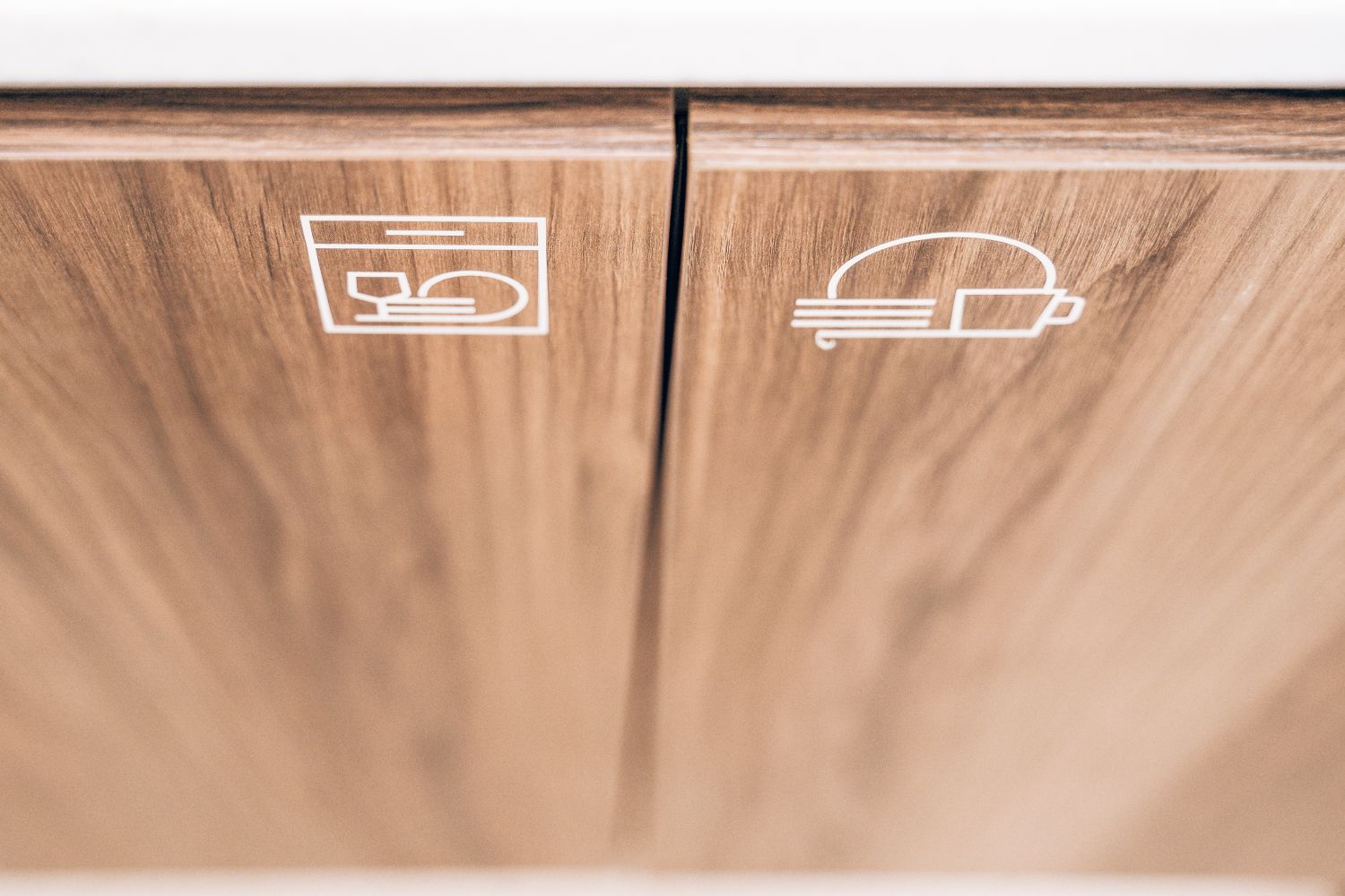 Kitchen amenity icons at Ellisse by Spacemade, produced as subtle surface cut vinyl graphics on timber cabinetry.