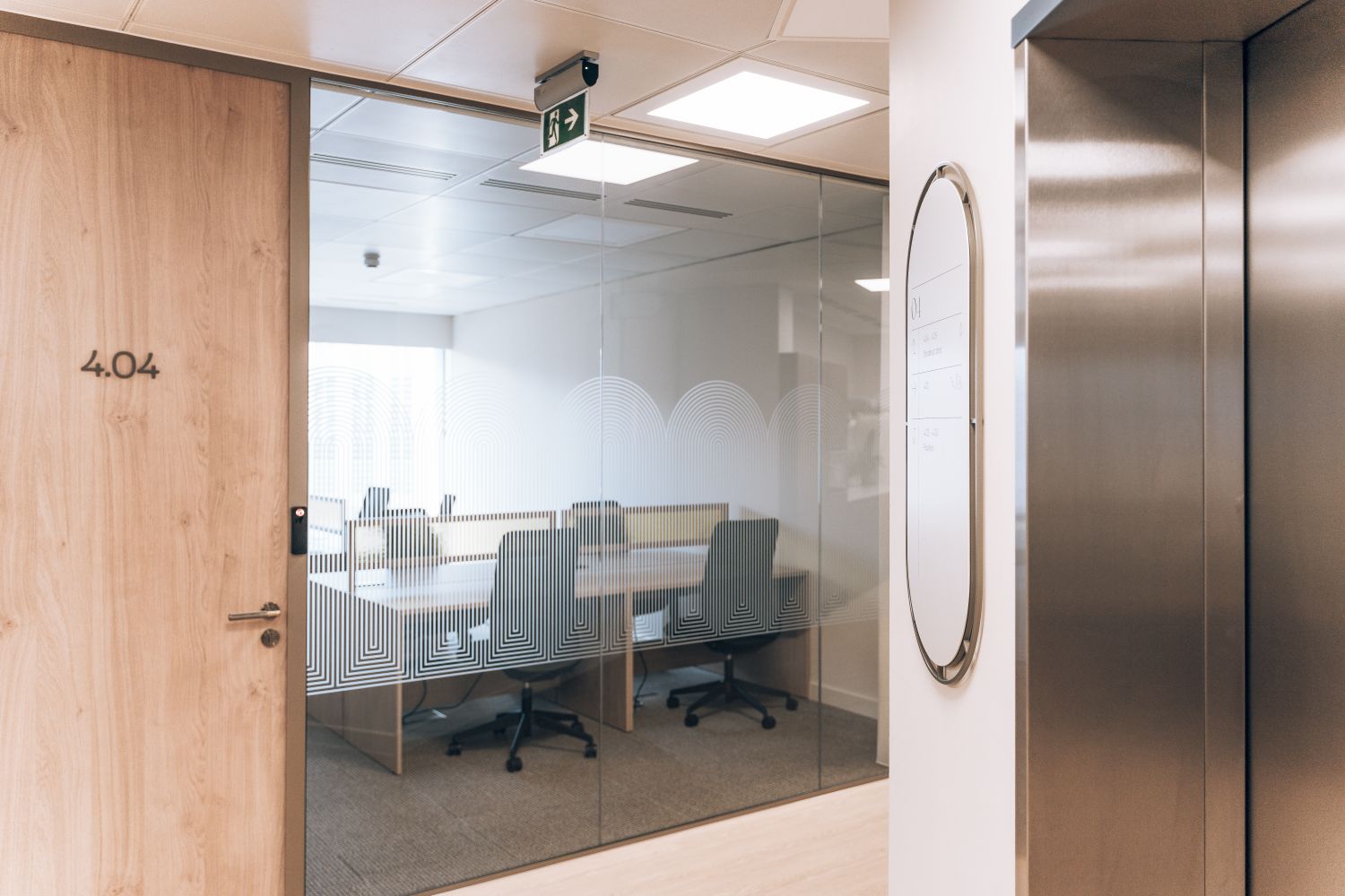 Ellisse office wayfinding and glass manifestation beside meeting room 4.04, integrated into the coworking space and lift lobby.