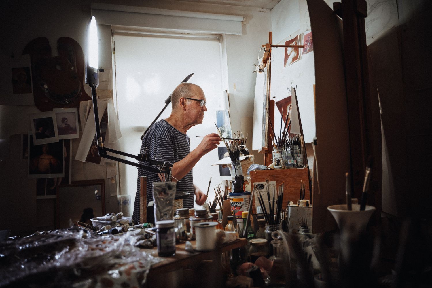 John Burke painting at the easel in his studio workspace which he calls 'The Box' during portrait process