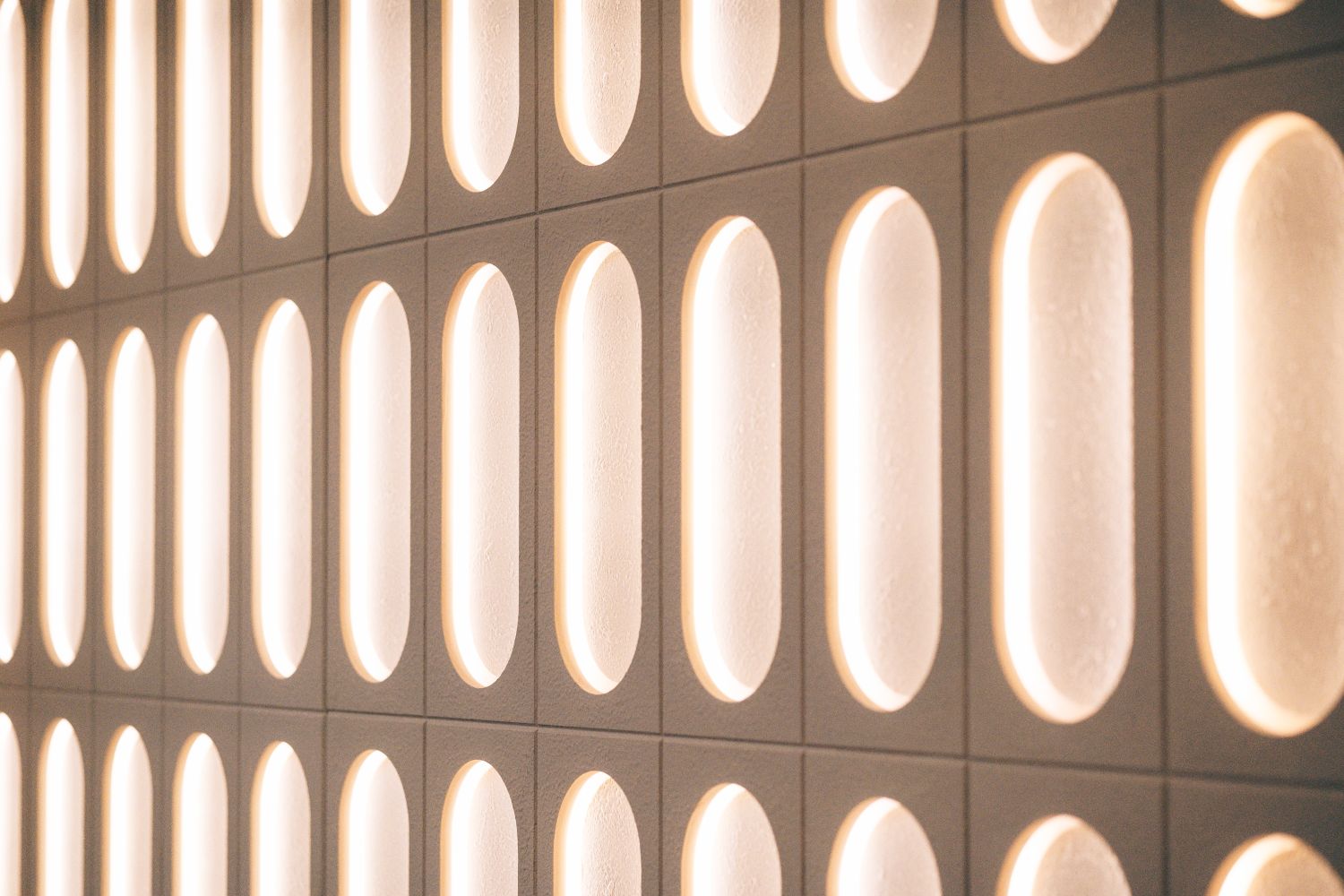 Close up of the custom illuminated reception wall at Ellisse, showing repeated ellipse forms and warm halo lighting.