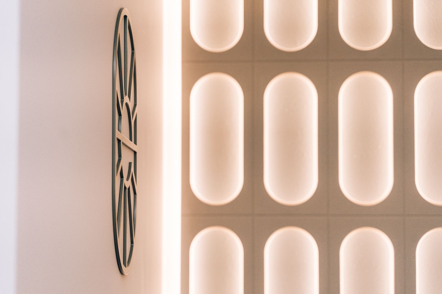 Side view of the bespoke metal Ellisse logo beside the illuminated reception wall at the Spacemade coworking space.