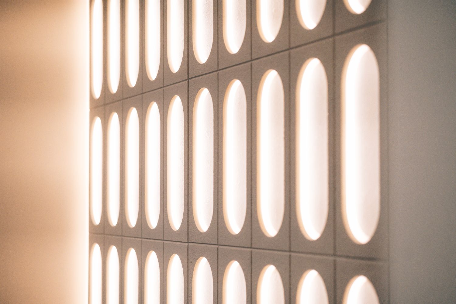 Art Deco inspired illuminated reception wall at Ellisse by Spacemade, using repeated ellipse shapes across the custom built installation.