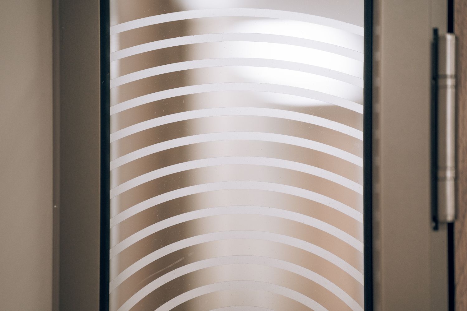 Detail of the cut vinyl manifestation at Ellisse, showing the layered curved lines used across the workplace glazing.