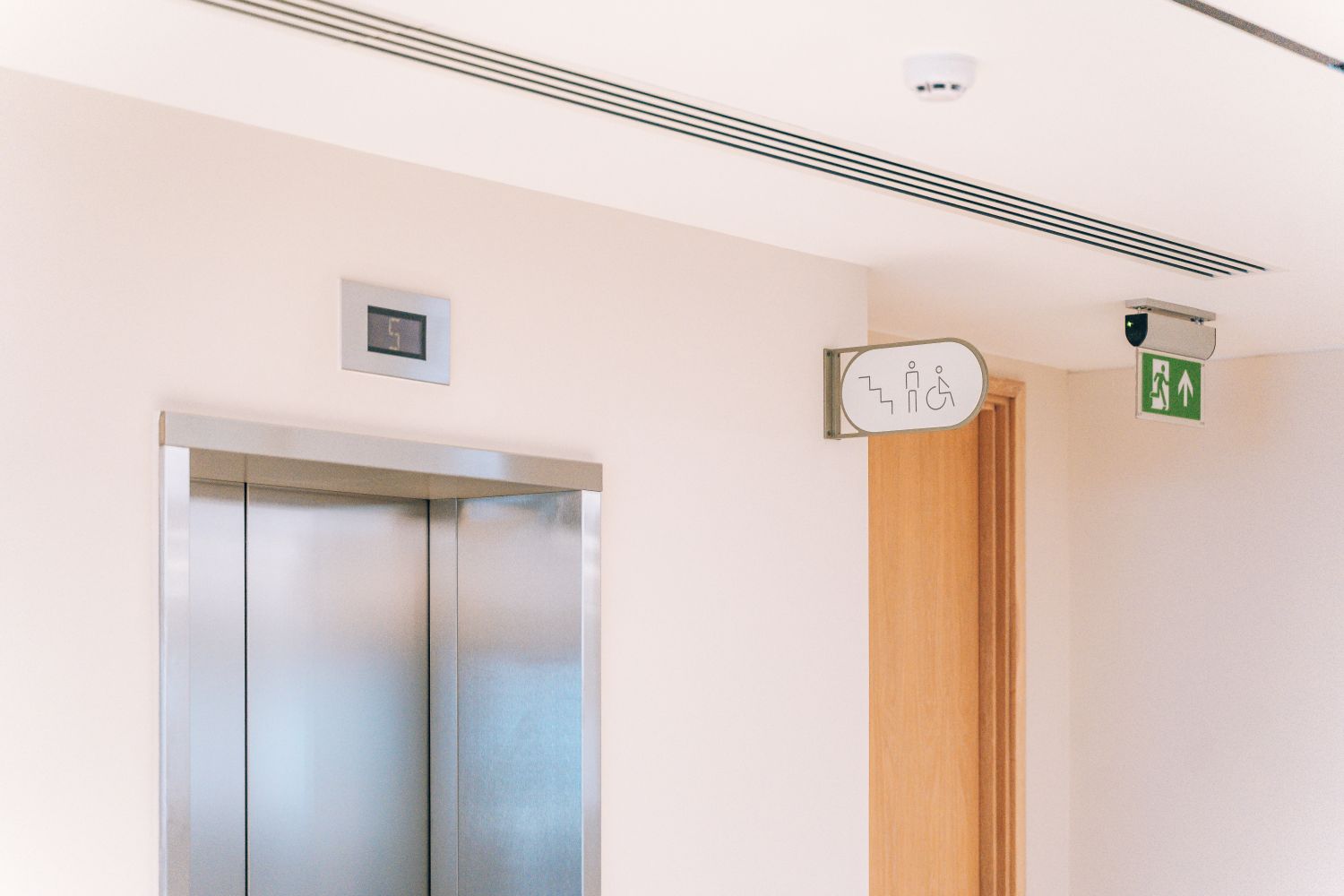 Double-sided projecting wayfinding sign at Ellisse by Spacemade, positioned beside the lifts for clear navigation.