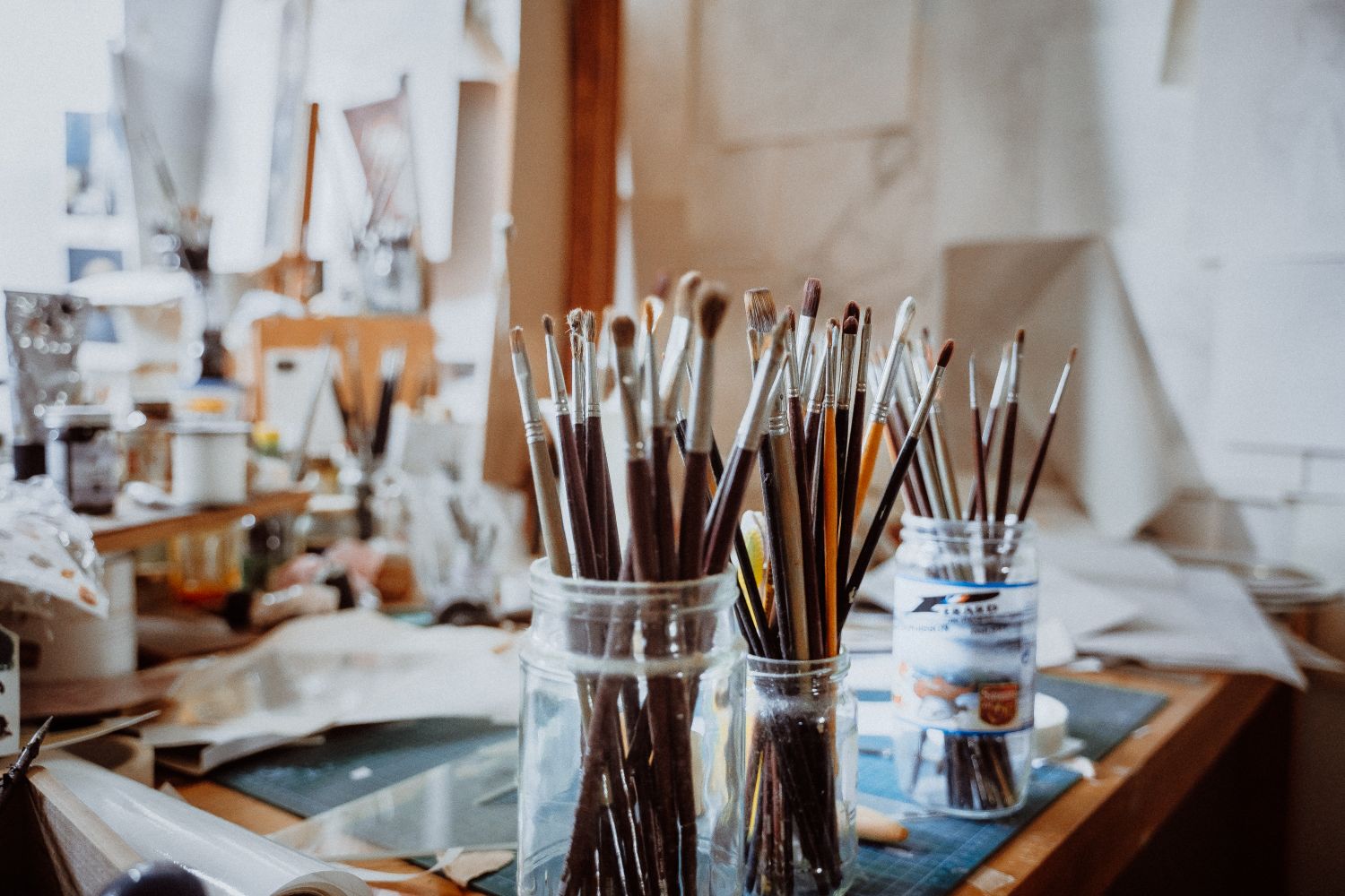 Paintbrushes in jars inside portrait artist John Burke’s London studio workspace