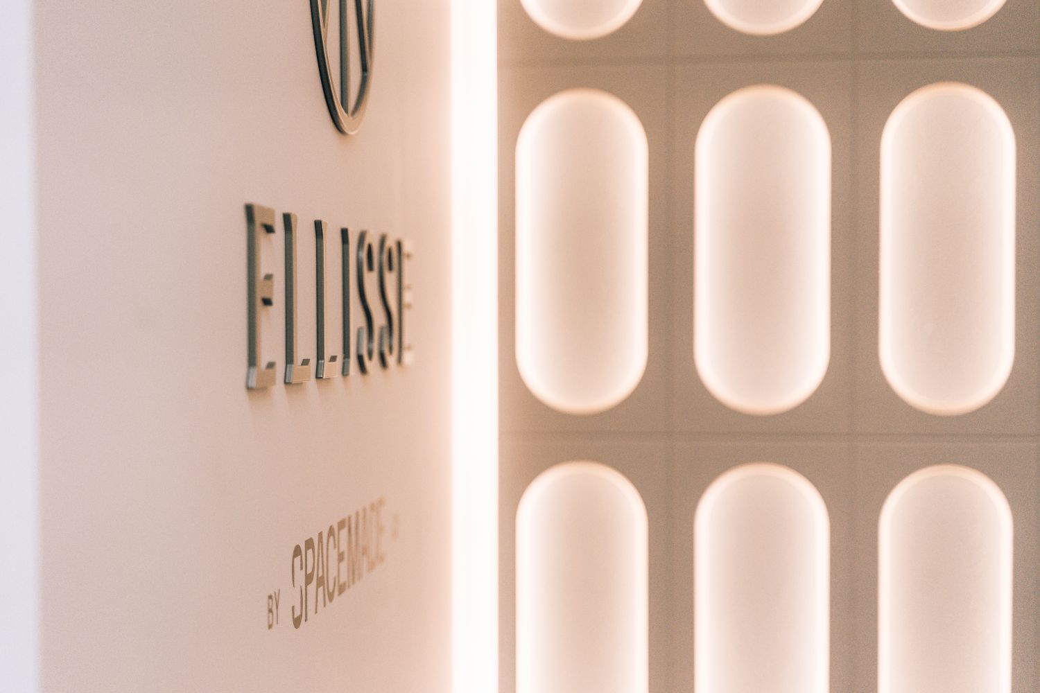 Bespoke Ellisse metal reception logo beside the illuminated Art Deco inspired feature wall.