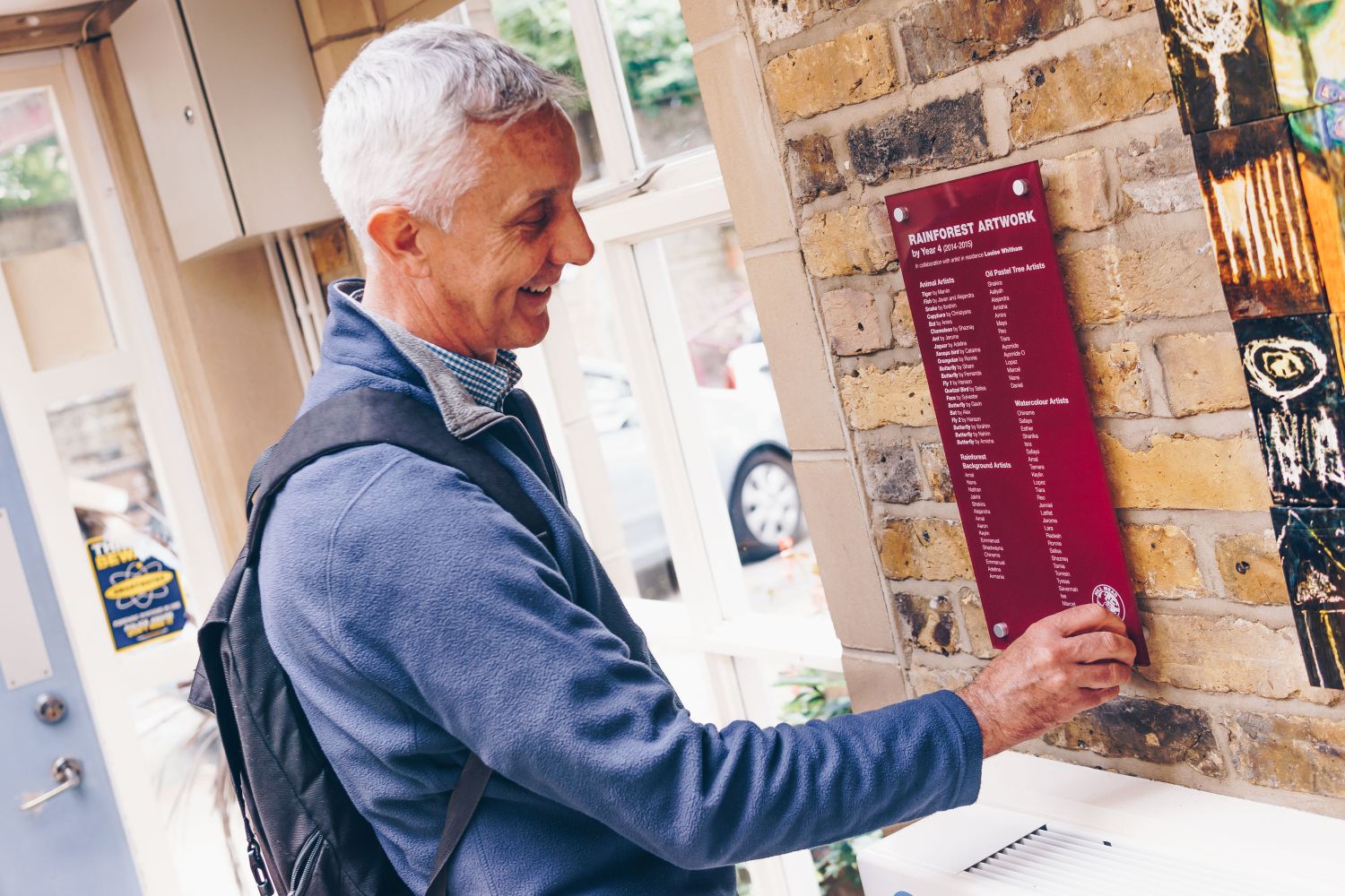 A dark red outdoor glass sign with metal stand off fixings.