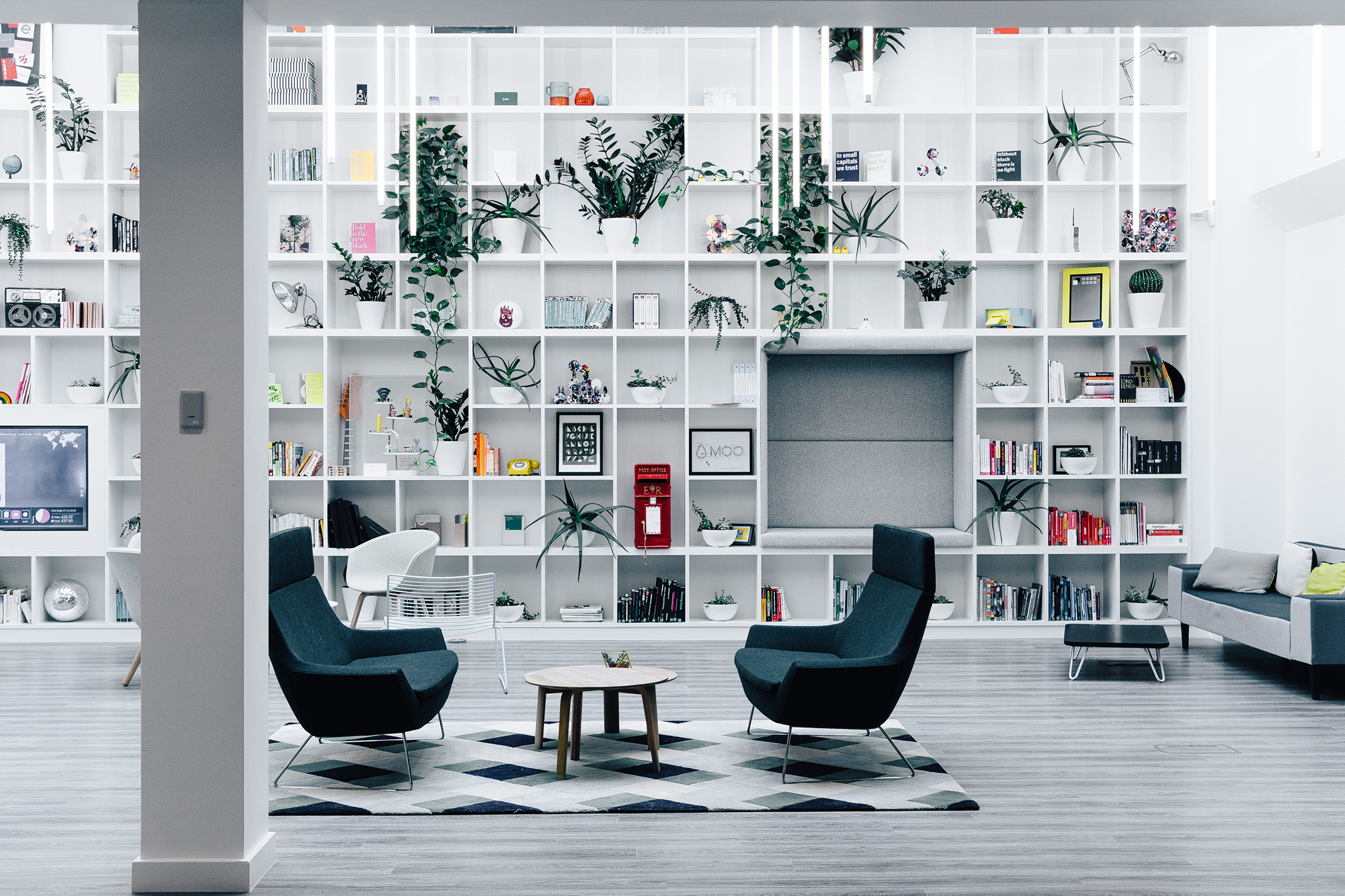 The black and white themed is used in a seating area with an airy backdrop of wall to ceiling white shelving.
