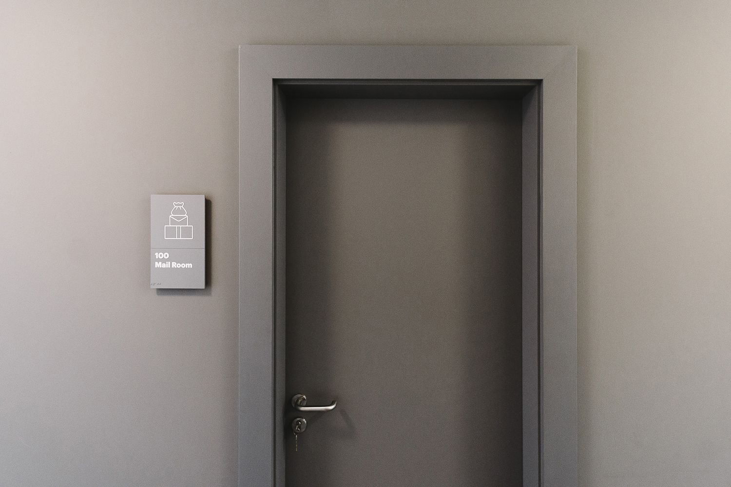 Picture of the door of a meeting room showing a grey braille wayfinding sign at Etsy London offices in Clerkenwell