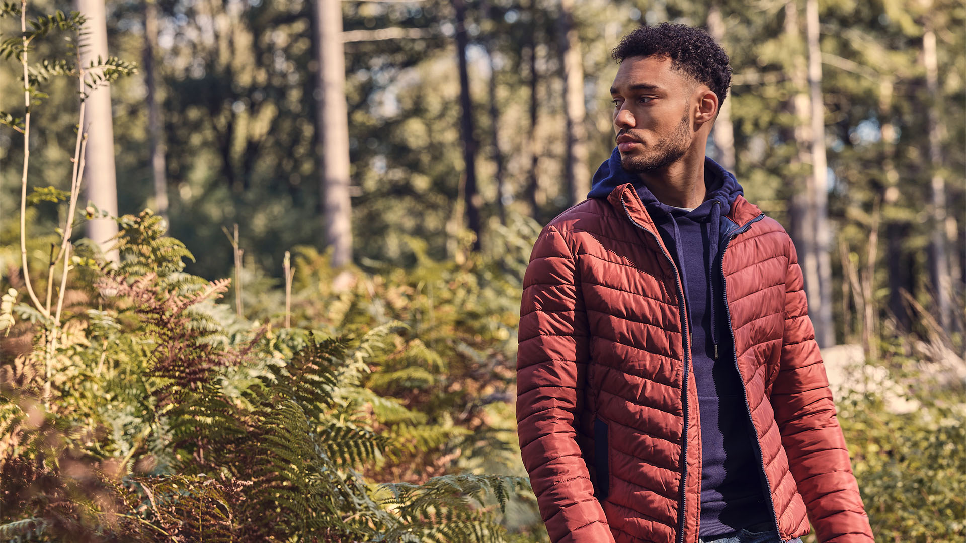 Model in de bossen met rode gewatteerde jas