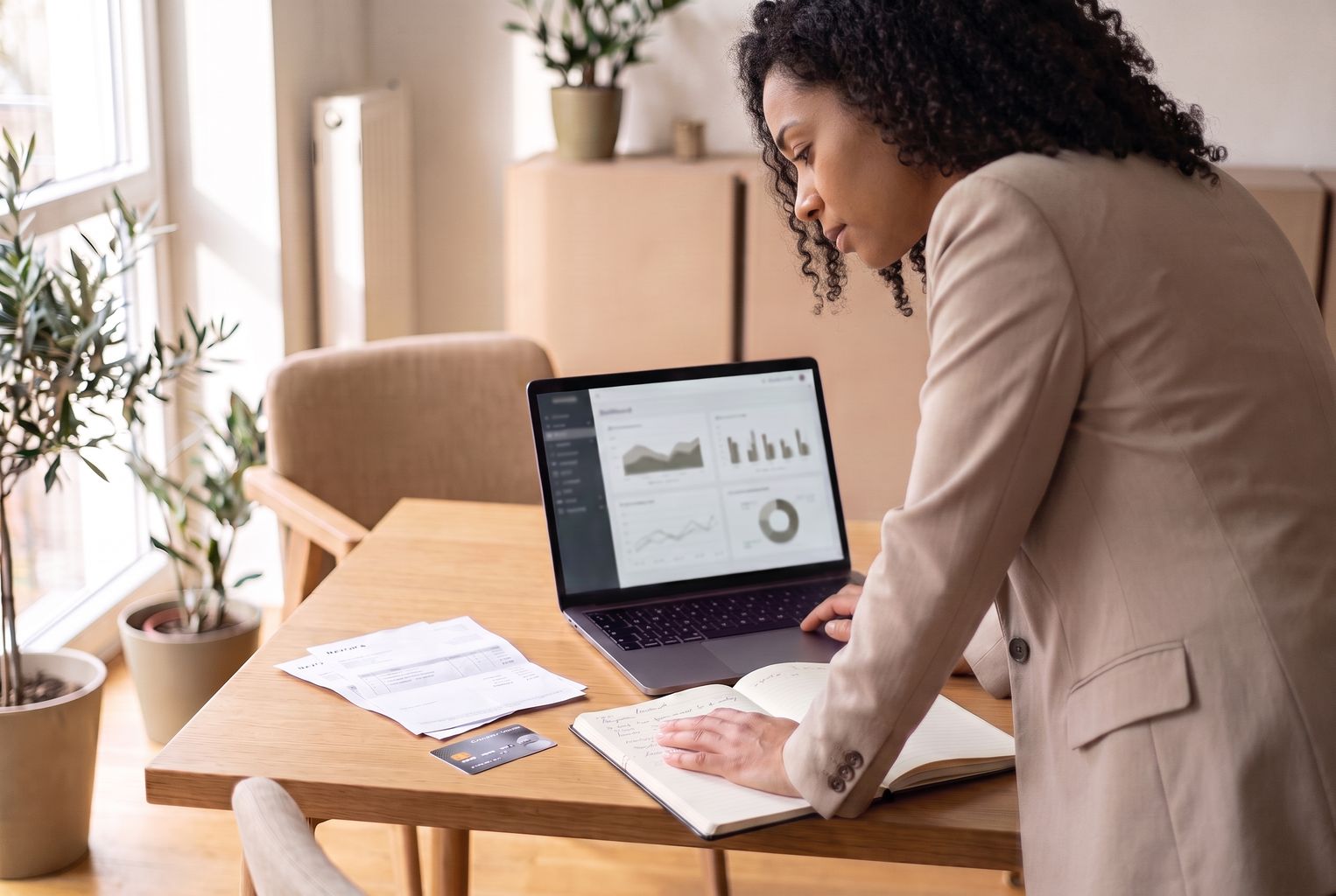 Finanzmitarbeiterin blickt konzentriert auf den Laptopbildschirm und prüft eine Übersicht zu Softwareausgaben und wiederkehrenden Abos. Auf dem Schreibtisch liegen Rechnungen, ein Notizbuch und eine Firmenkarte.