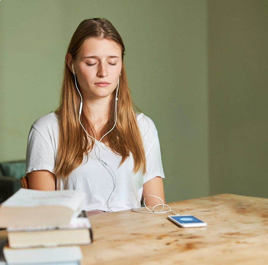 Een vrouw mediteert, ziet er ontspannen en gelukkig uit in een prachtig ingerichte kamer.