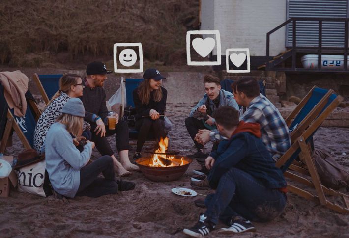 Ein Gruppe von junge Menschen sitzt um eine Feuerschale und unterhält sich.