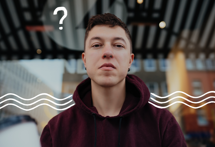 Eine männlich gelesene Person mit kurzen, braunen Haaren und braunen Augen schaut leicht von oben in die Kamera und trägt einen roten Hoodie. Im Hintergrund sieht man Häuser. Außerdem weiße Scribbles in Form von Wellen und einem Fragezeichen.